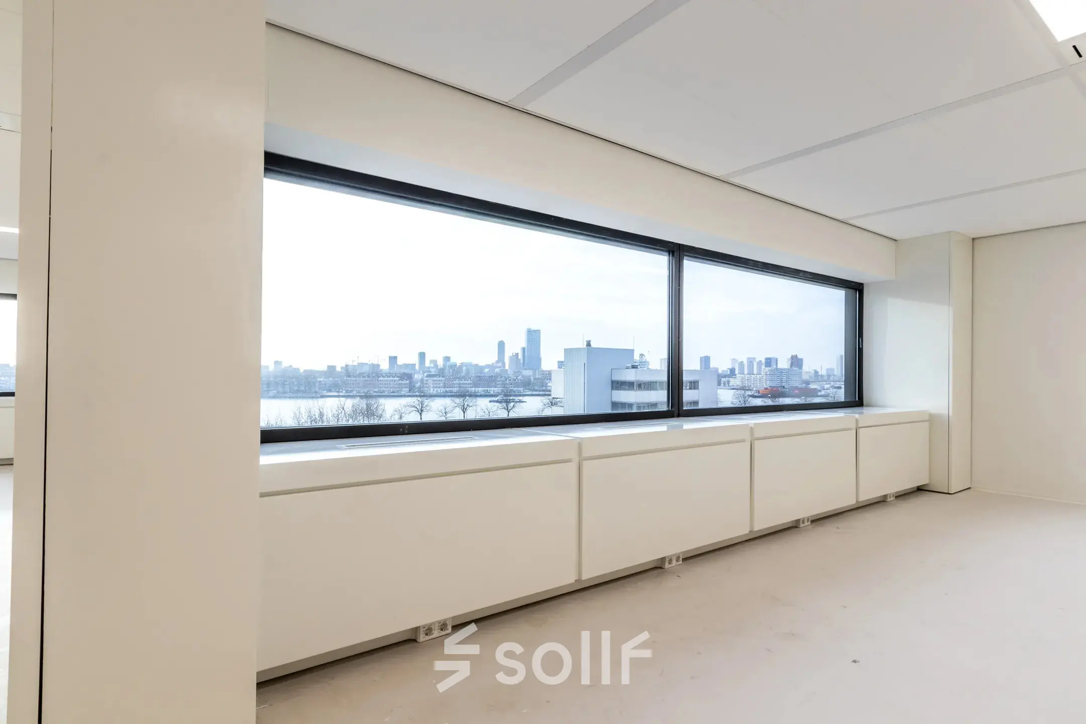 Interior view of an unfurnished office space with large windows offering a panoramic view of Rotterdam skyline at Oostmaaslaan 71.