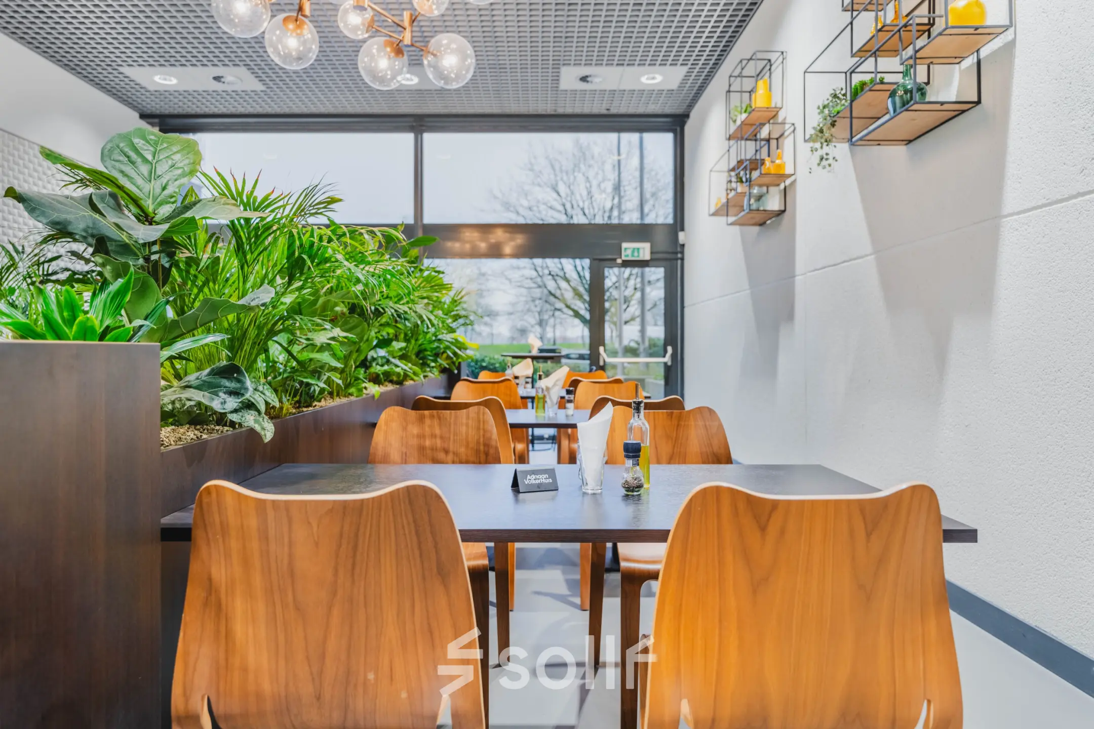 Modern furnished lounge area with tables and plants at an office space rental on Oostmaaslaan 71, Rotterdam Kralingen.