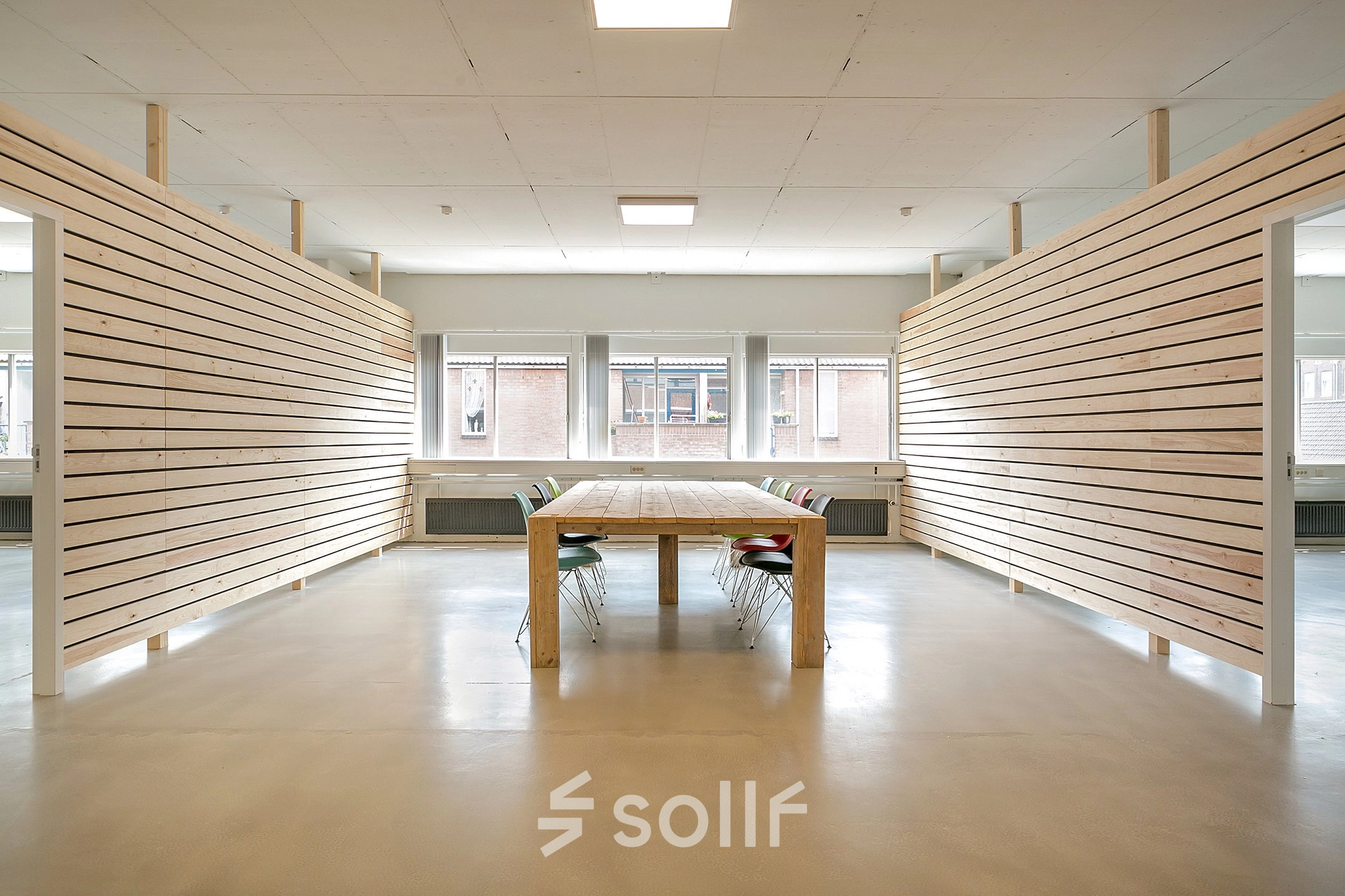 Modern office interior at Linker Rottekade 292, Rotterdam North, with a minimalist design featuring a long wooden table and chairs, perfect for meetings or collaborative workspace. Ideal for office space rental.