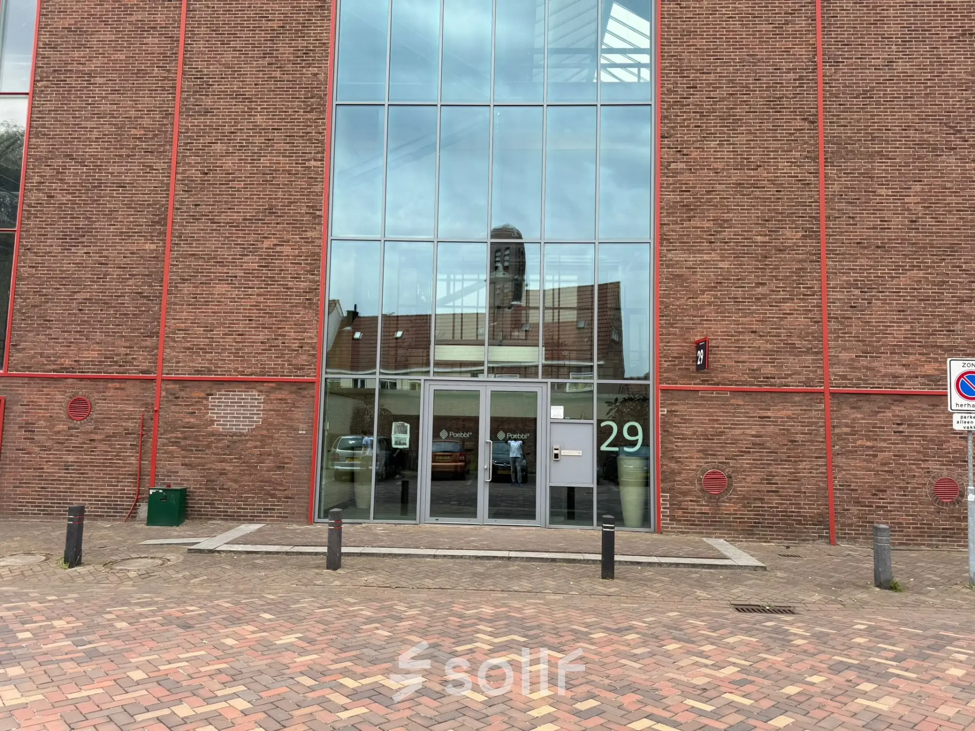 Exterior view of the office building at Scheepsbouwweg 29, Rotterdam Waalhaven, showcasing a modern glass entrance suitable for those seeking office space rental.