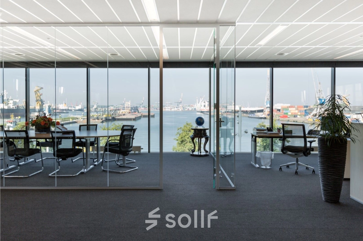 Modern office space rental at Waalhaven O.z. 83, Rotterdam Waalhaven, featuring expansive glass walls with harbor views and sleek furnishings in a meeting area.