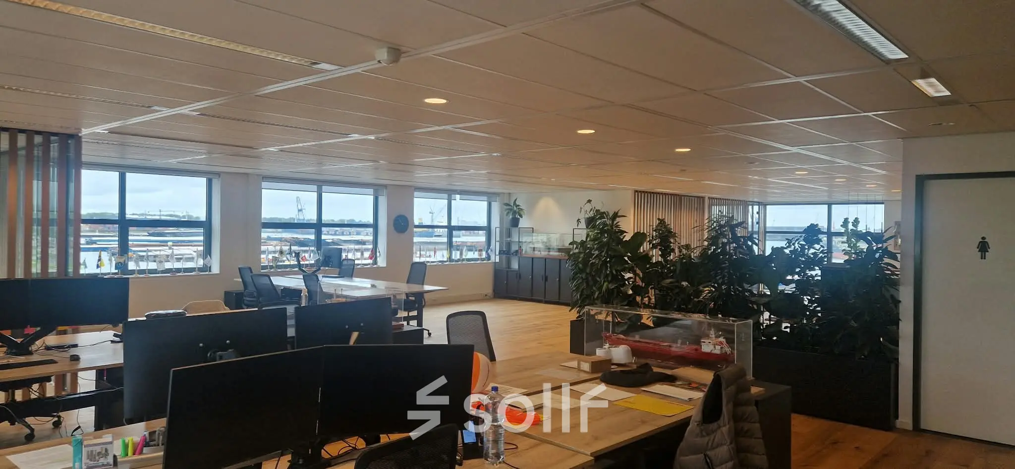 Spacious office space with large windows offering natural light, featuring desks and chairs, at Waalhaven Zuidzijde 21, ideal for office space rental.