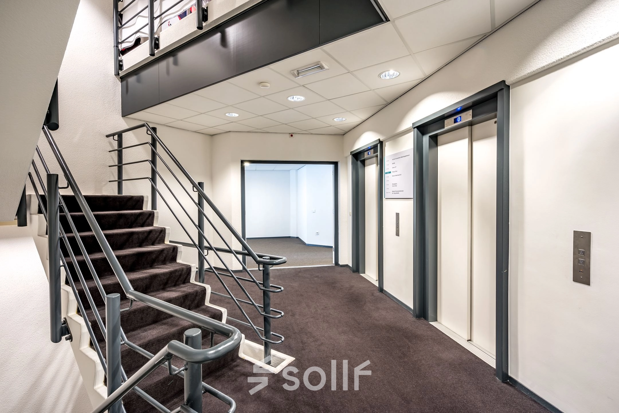 Interior view of a modern office building at Overschieseweg 304-332, Schiedam, featuring an open area with elevators and a staircase, ideal for efficient office space rental.