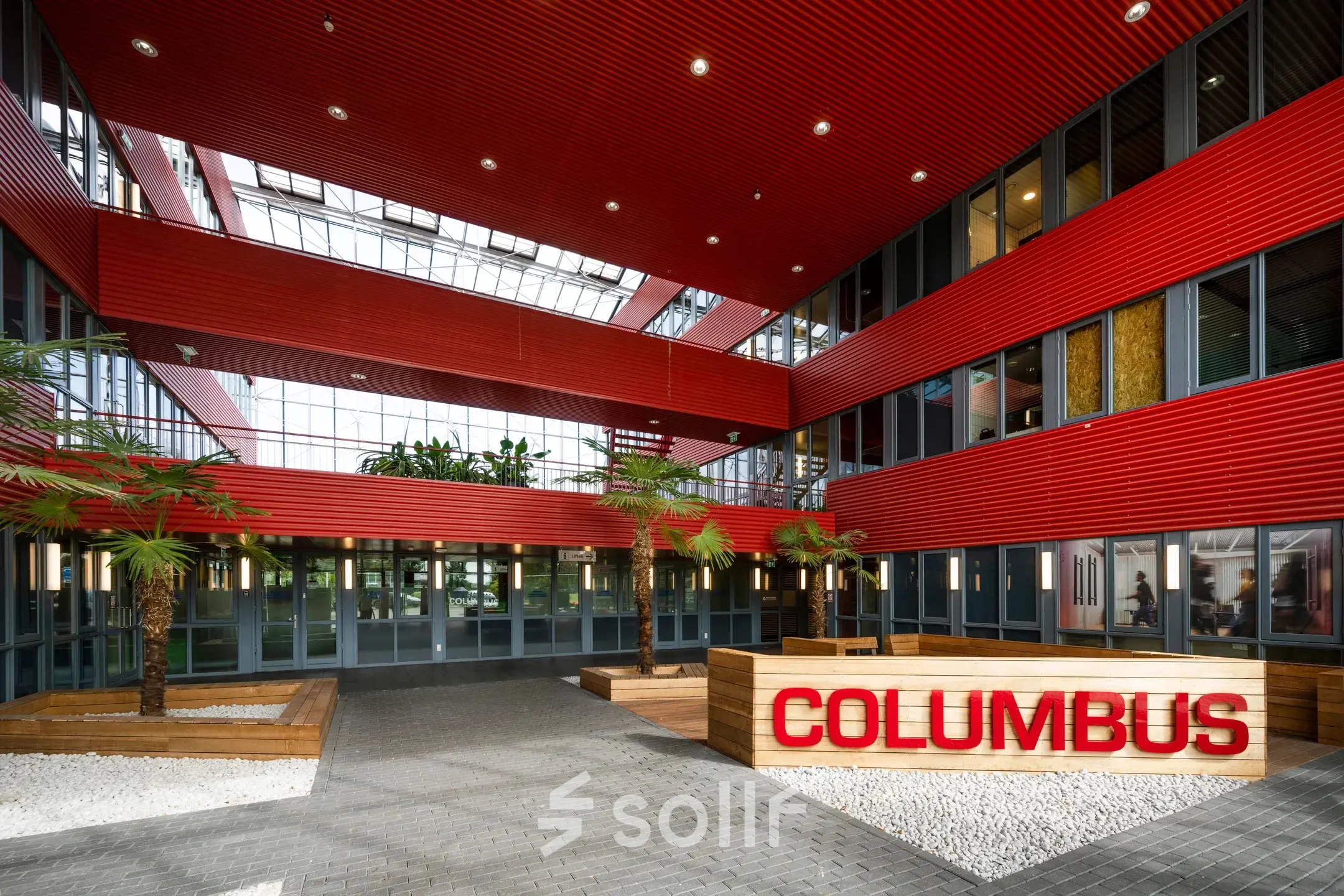 Modern office entrance with red and grey architectural design and skylight in Schiphol Airport for office space rental.