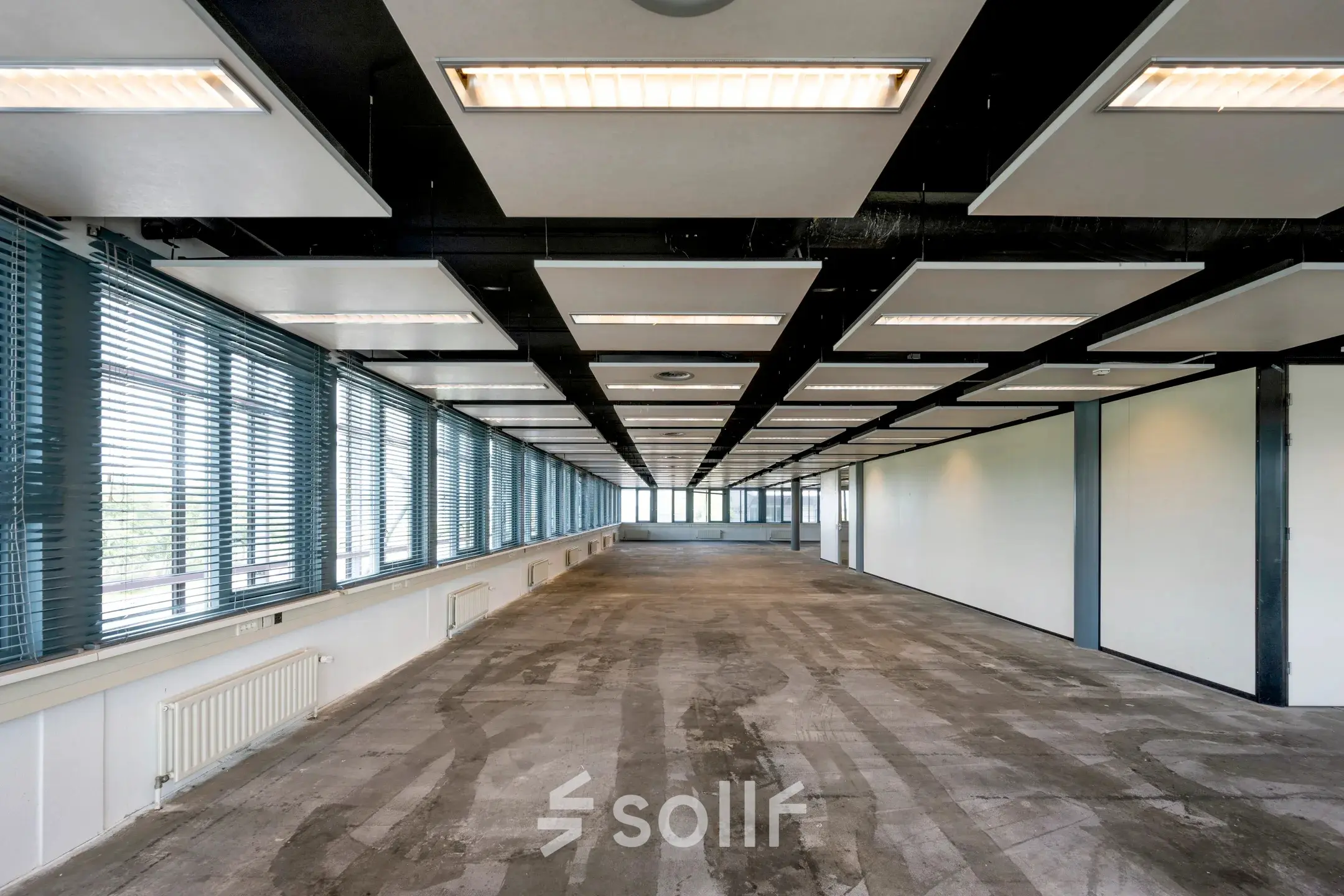 Unfurnished office space with large windows and modern ceiling design, available for rent at Folkstoneweg 2-56, Schiphol Airport.