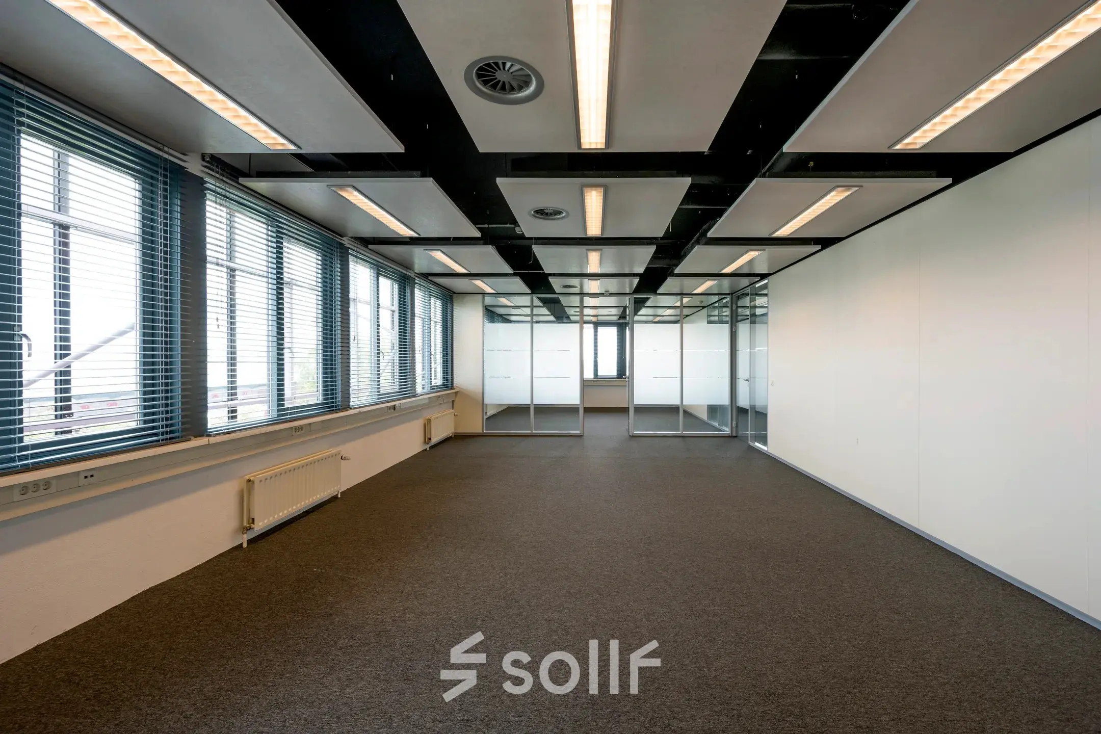 Spacious, unfurnished office space at Schiphol Airport, featuring large windows and modern lighting, available for rent.
