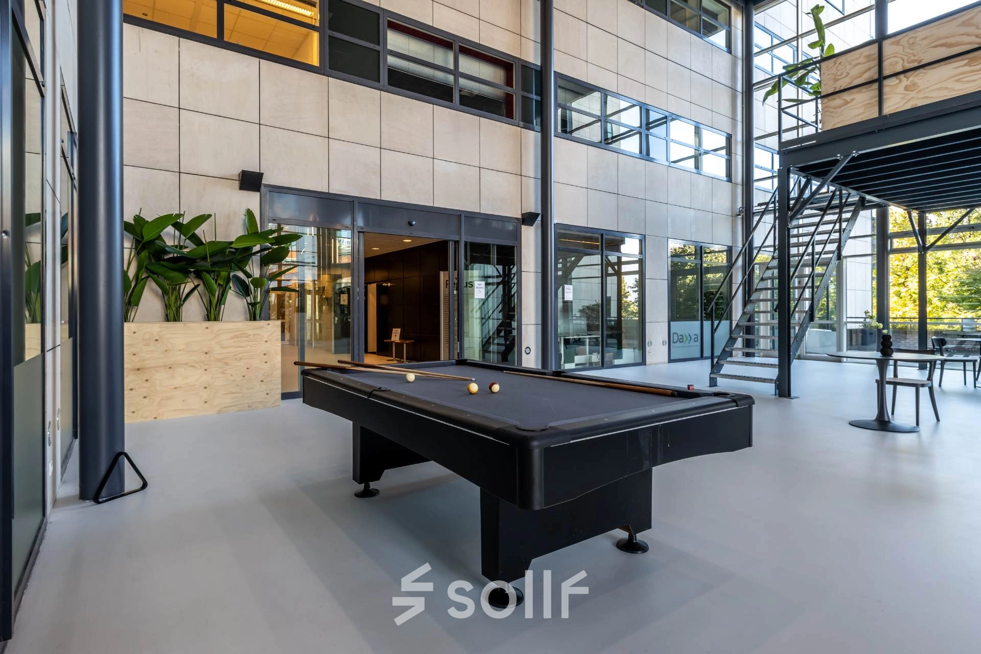 Modern office space at Beechavenue 54-100, Schiphol Rijk, featuring a pool table and seating area for rent. Light-filled interior with large windows, perfect for office space rental.