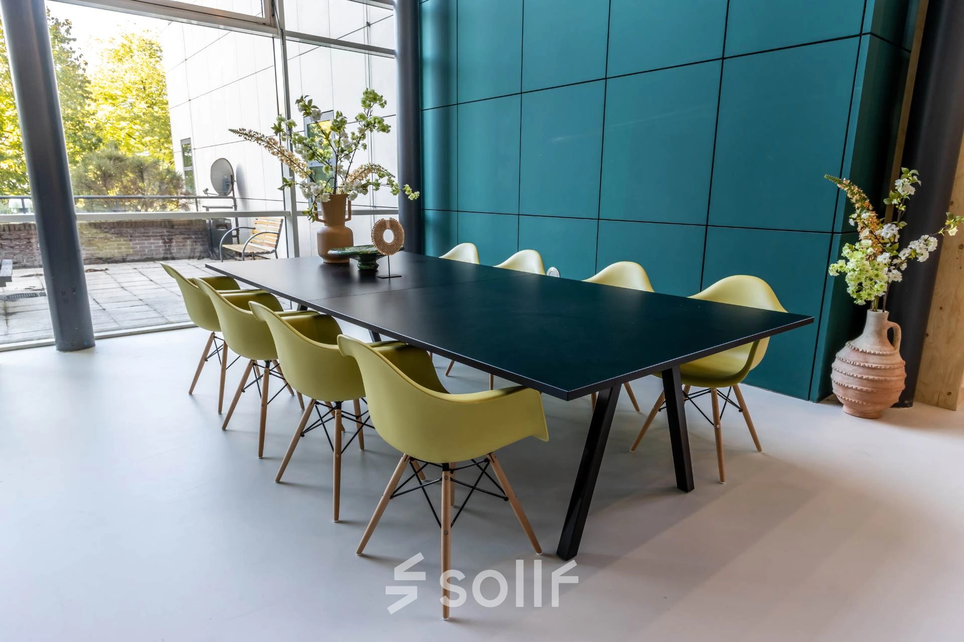 Modern office space rental at Beechavenue 54-100, Schiphol Rijk featuring a long table with vibrant chairs and decorative elements, perfect for collaborative meetings.