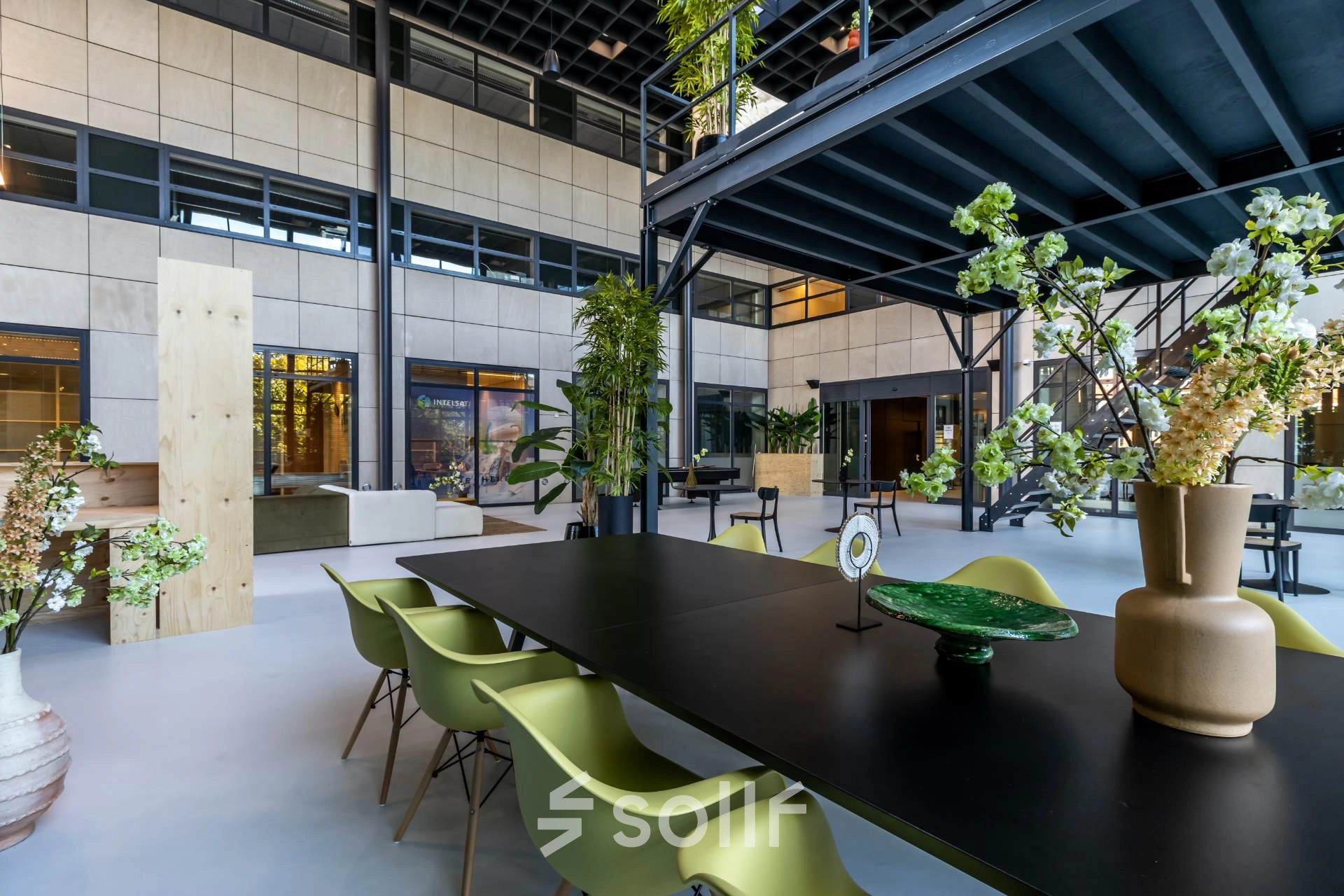 Spacious and stylish interior at Beechavenue 54-100, Schiphol Rijk, perfect for office space rental. Modern furnishings include green chairs and decorative plants, ideal for collaborative workspaces.