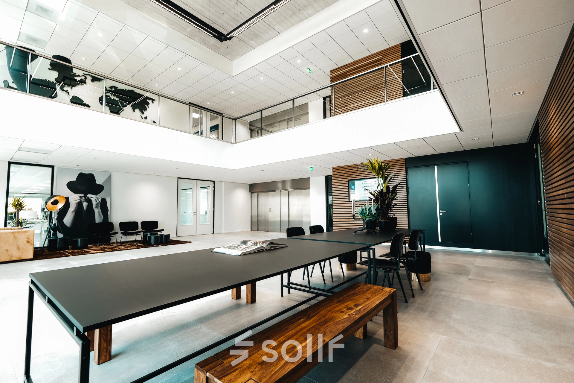 Modern office at Schiphol Rijk with a spacious meeting table and seating area, ideal for those looking to rent office space. Art decorates the walls, complementing the sleek design.