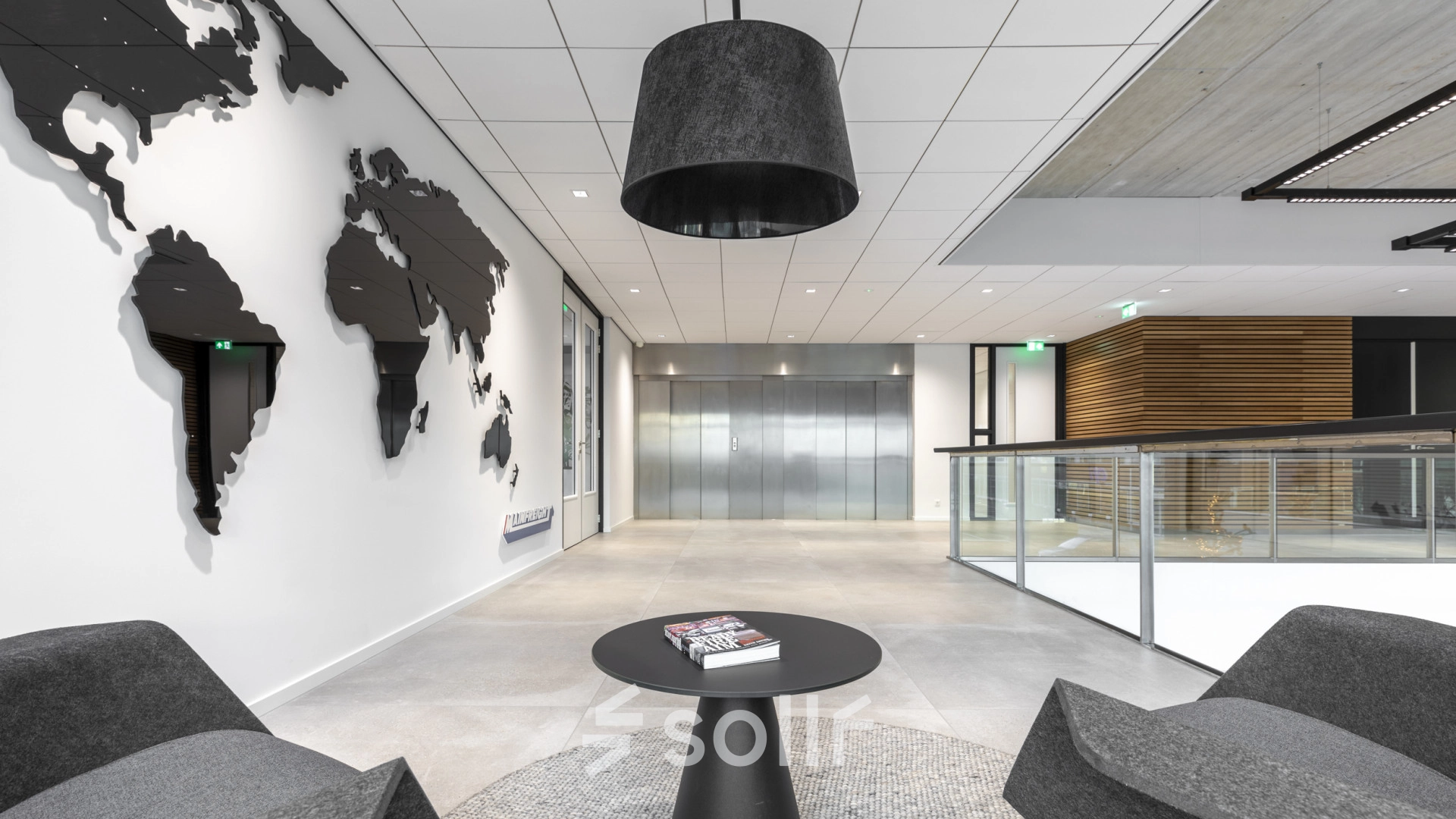 Modern office space at Tupolevlaan 81-99, Schiphol Rijk, featuring sleek seating, a world map wall decoration, and elevator access. Ideal for office space rental.