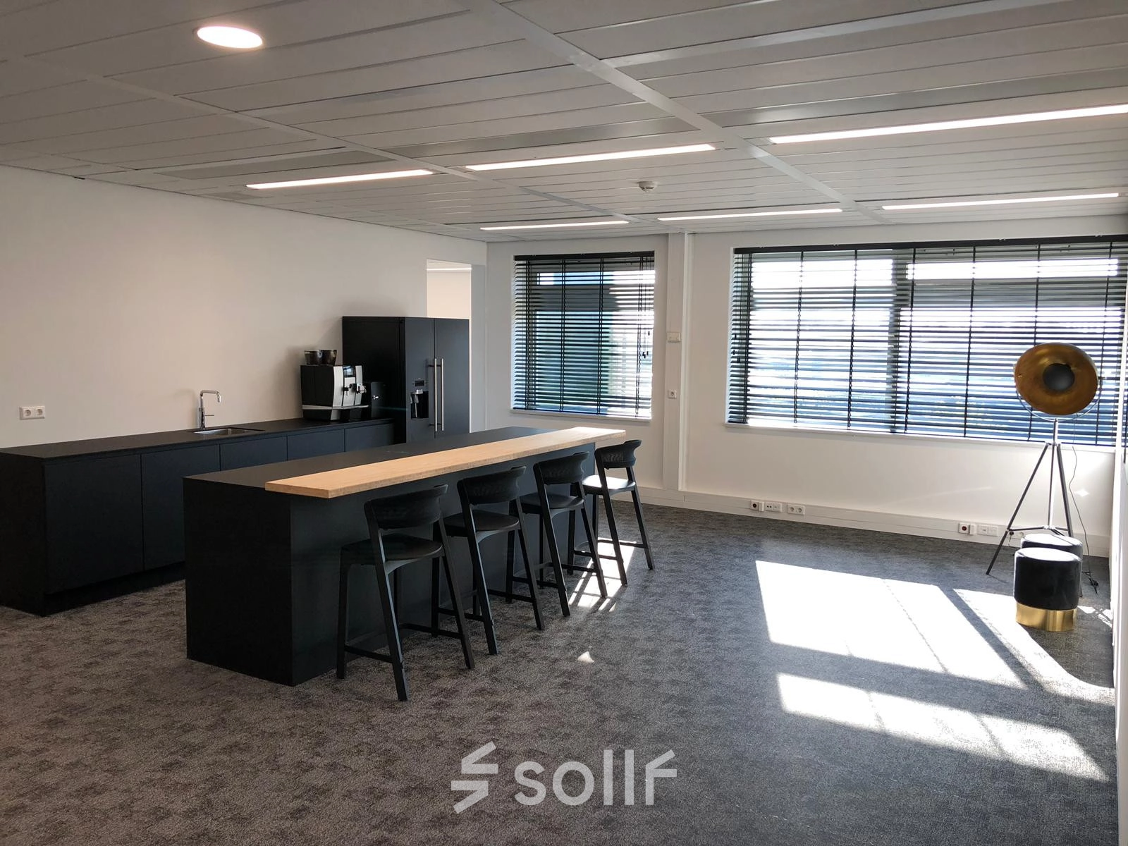 Spacious, well-lit office interior featuring a kitchenette with bar stools, perfect for office space rental in Schiphol Rijk at Tupolevlaan 81-99.