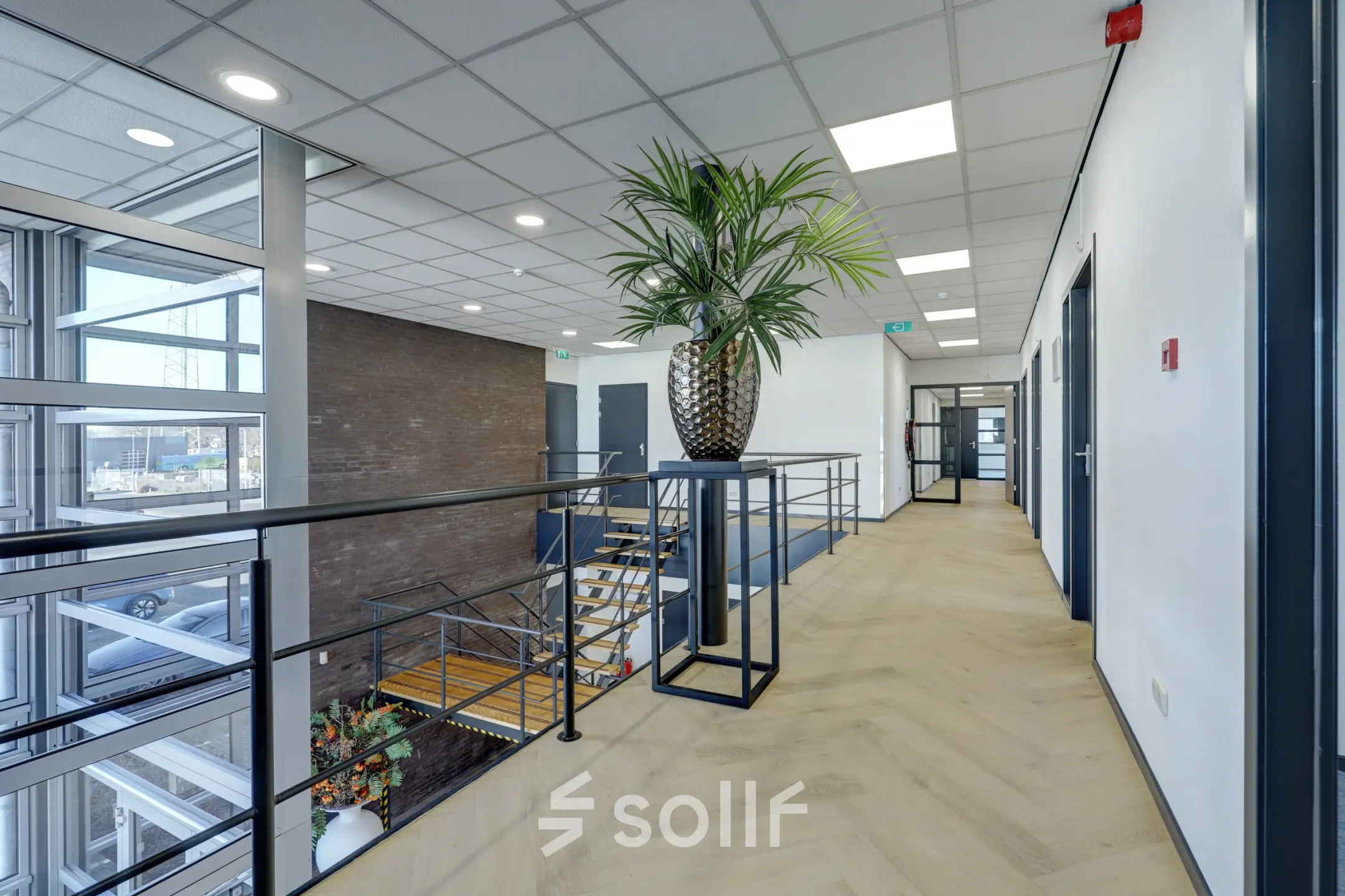 Bright corridor with large windows and a staircase at an office to rent at Fischerpad 106, Sittard. Ideal for office space rental.