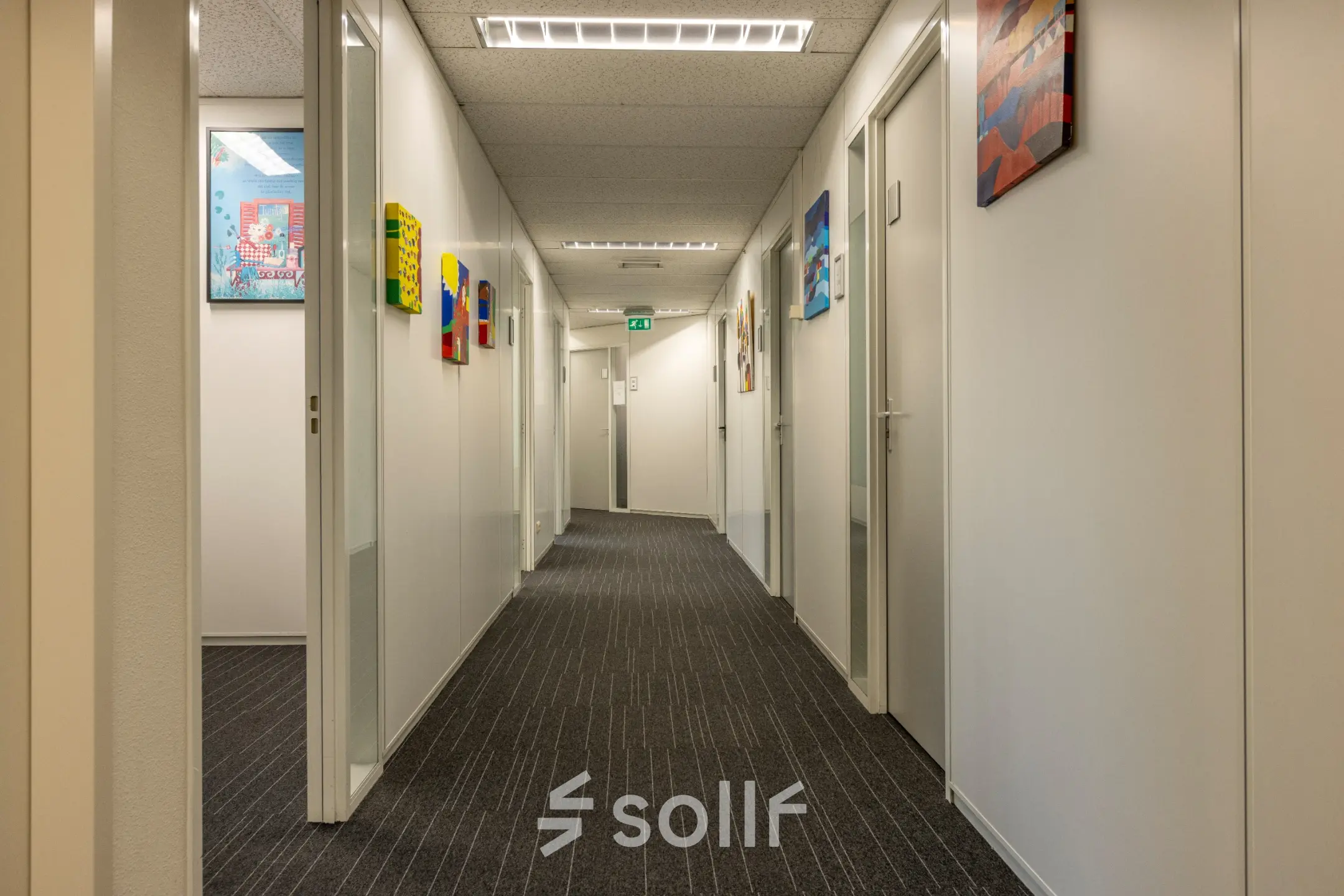 Hallway of an office for rent at Curieweg 9, Spijkenisse, showcasing framed artwork on walls and a modern ceiling. Ideal for those seeking office space rental.