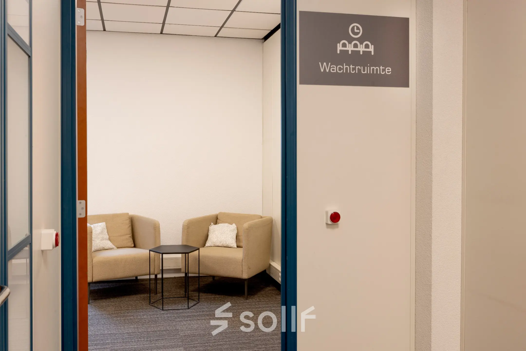 Cozy office space to rent at Curieweg 9, Spijkenisse, featuring a small waiting area with two beige armchairs and a round black table.