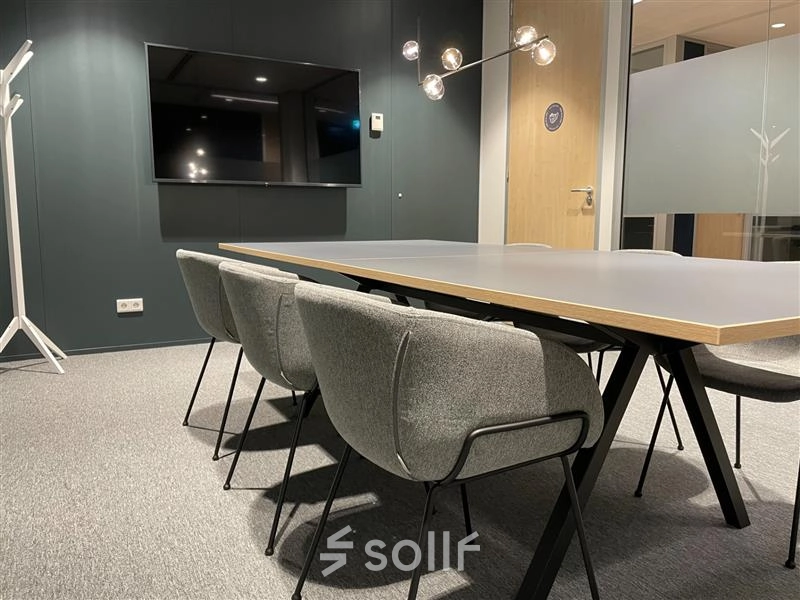 Modern conference room with a sleek table, comfortable chairs, and a wall-mounted TV, suitable for office space rental in The Hague Center at Alexanderveld 5-9.