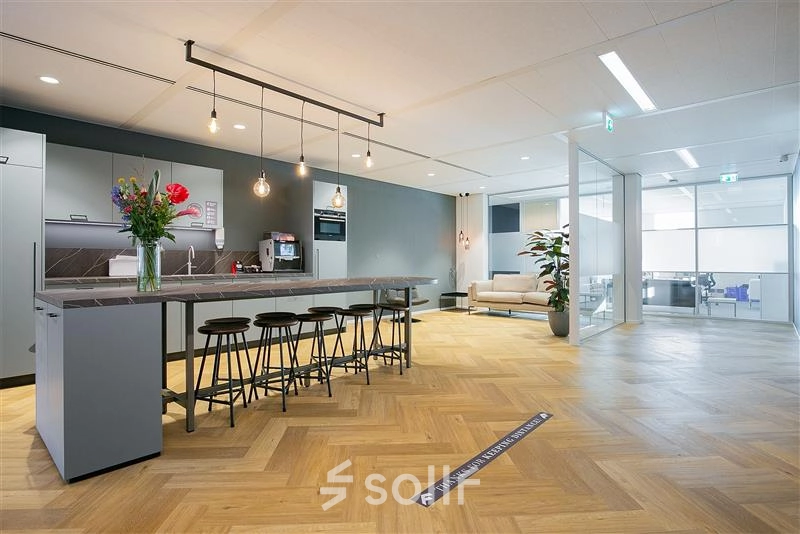 Spacious office interior at Alexanderveld 5-9 in The Hague Center, featuring a modern pantry area with counter seating and a lounge space. Ideal for office space rental with stylish furnishings and open layout.