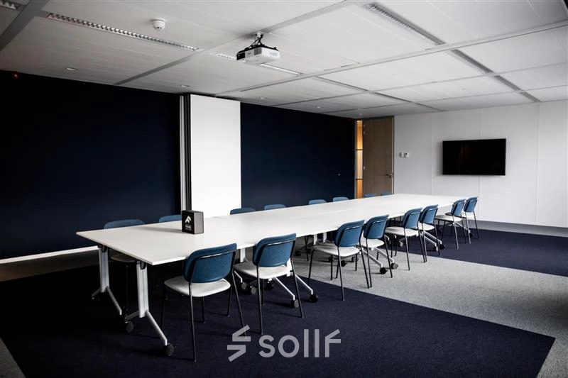 Spacious conference room at Alexanderveld 5-9, The Hague, featuring a long table with chairs suitable for meetings. Ideal for office space rental with modern amenities.