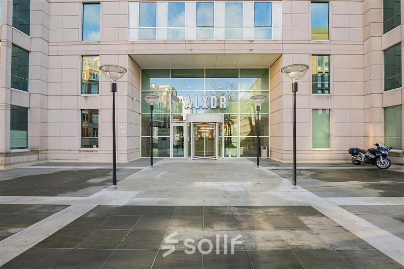 Entrance of an office building at Alexanderveld 5-9 in The Hague Center, showcasing a modern facade with large glass doors, ideal for office space rental.