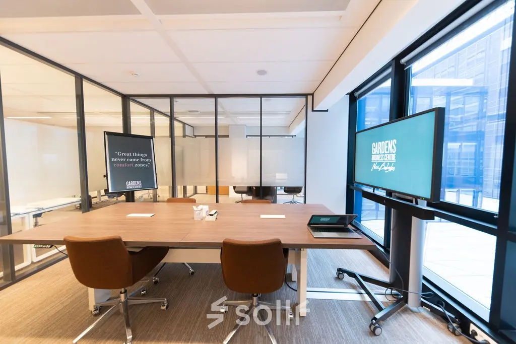 Modern office space to rent at Anna van Buerenplein 41, The Hague Center, featuring a furnished meeting area with digital displays and large windows.