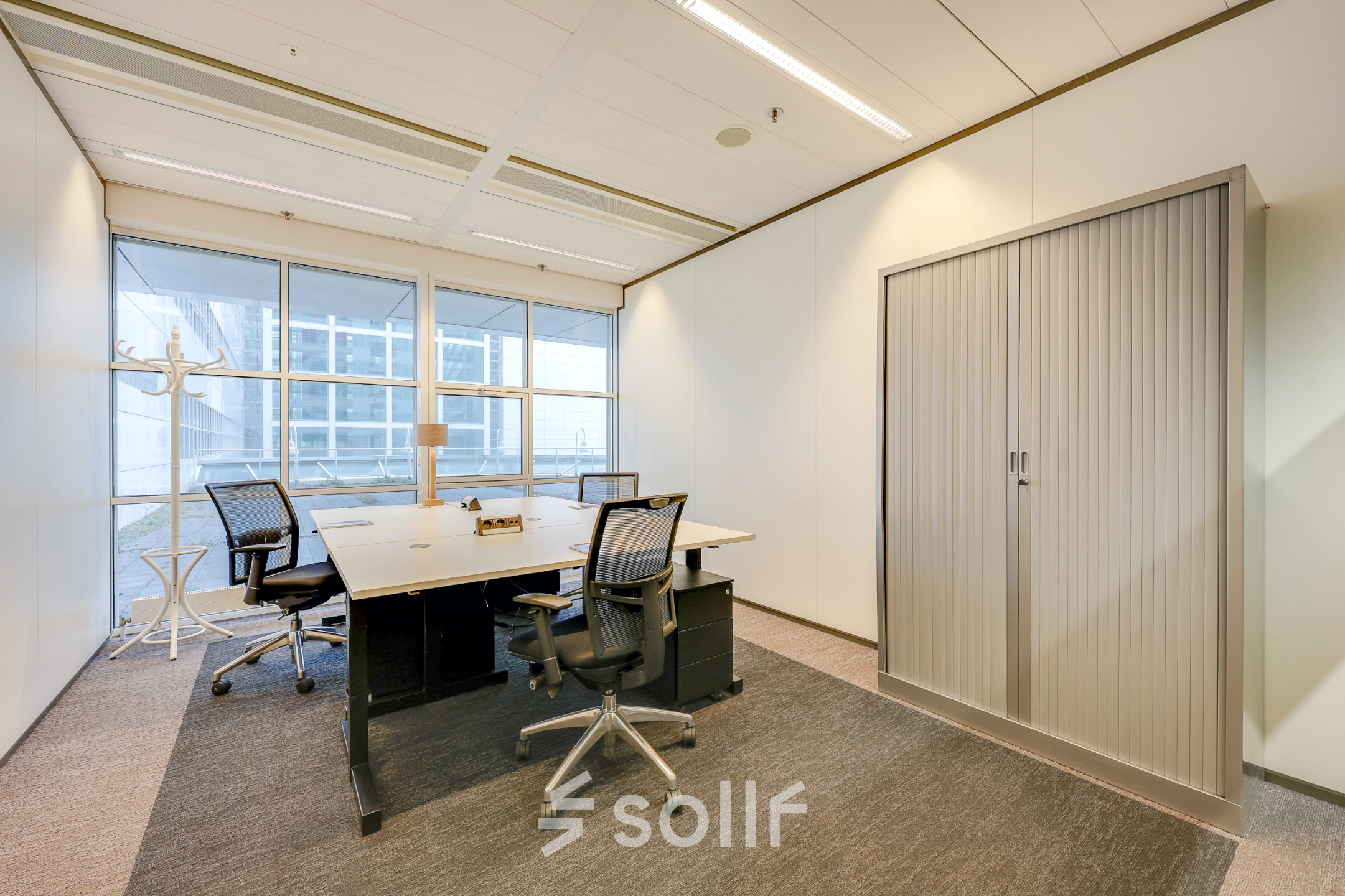 Bright office space at Kalvermarkt 53, The Hague Center, featuring a desk with chairs and large windows. Ideal for office space rental.