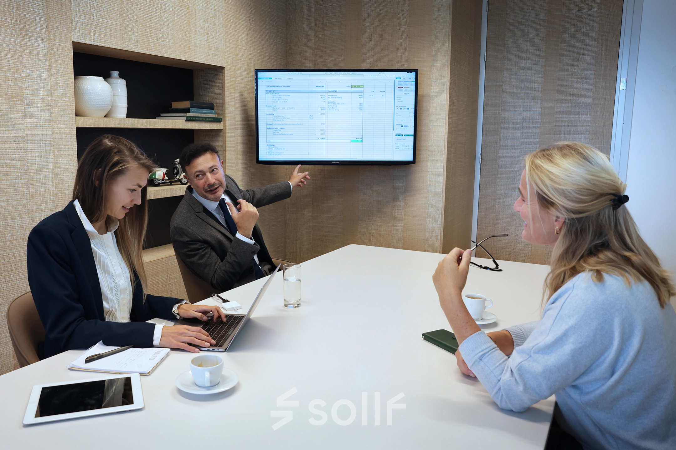 Colleagues in The Hague Center discuss project details in a modern conference room at Koninginnegracht 19. Ideal office space rental for collaborative meetings.
