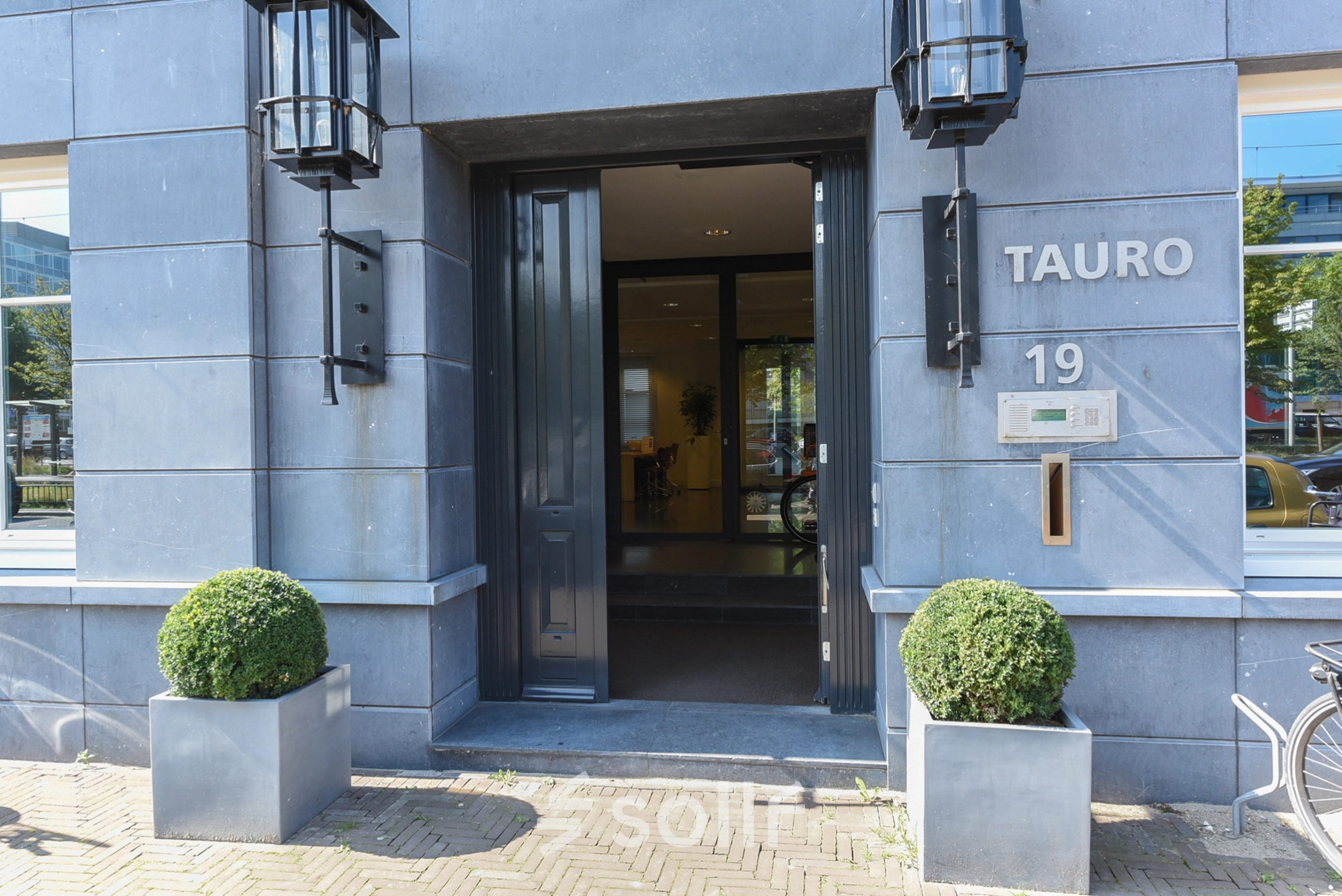 Entrance to office space rental at Koninginnegracht 19, The Hague Center featuring modern exterior with planters.
