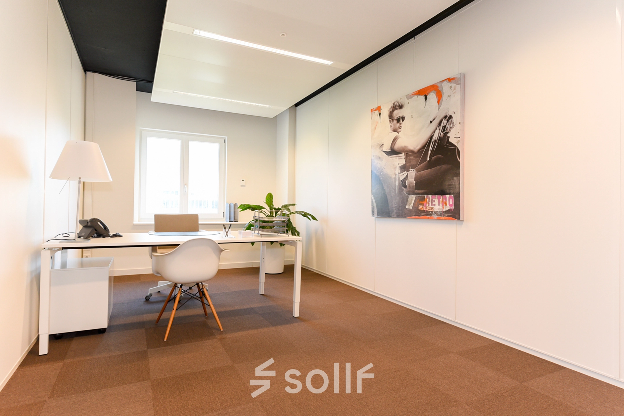 Bright office space with a large desk, modern chair, and artwork on the wall at Koninginnegracht 19, ideal for rent office space in The Hague Center.