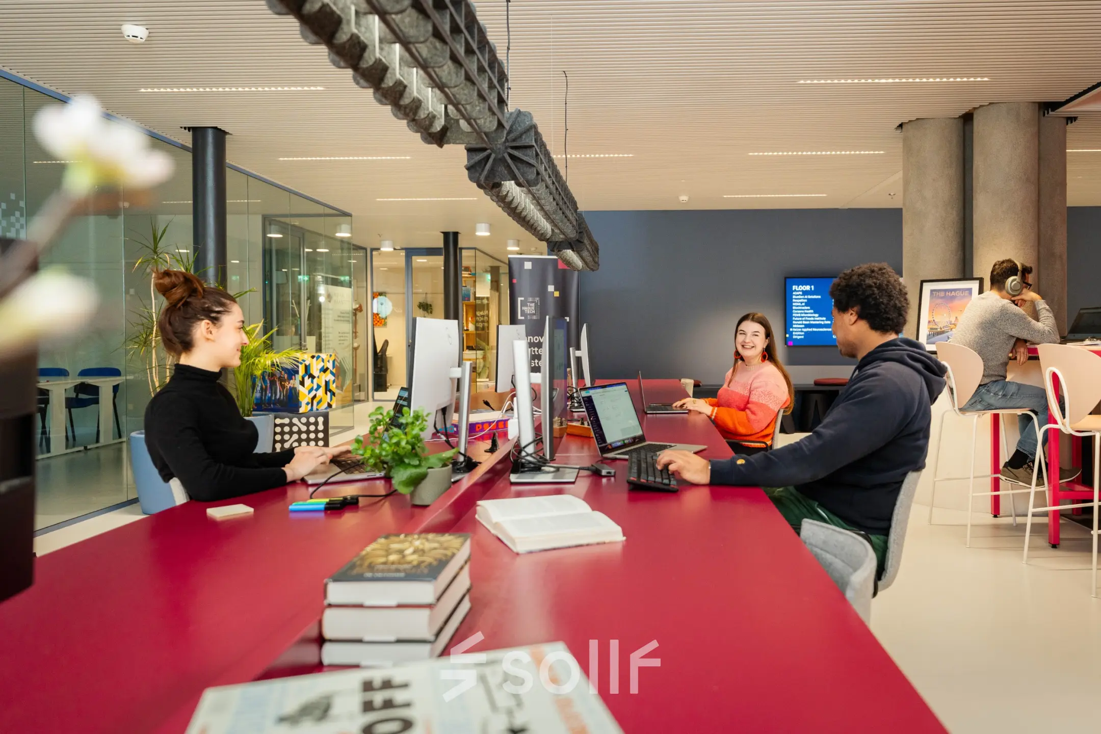 Bright, modern workspace at Waldopstraat 5, The Hague Center, with professionals engaged in discussions and computer work. Ideal office space rental for collaborative activity.