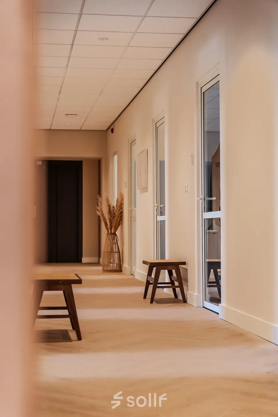 Modern office hallway at Zeestraat 100, The Hague Center, featuring wooden benches and soft lighting, ideal for office space rental.