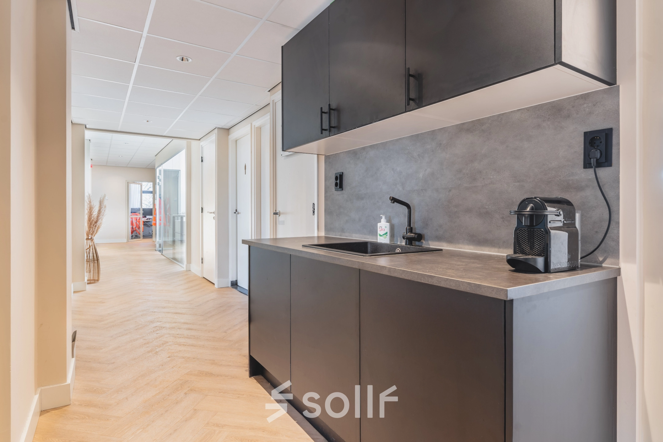 Modern kitchenette in Zeestraat 100 office space with sleek cabinets and coffee machine, perfect for office space rental in The Hague Center.