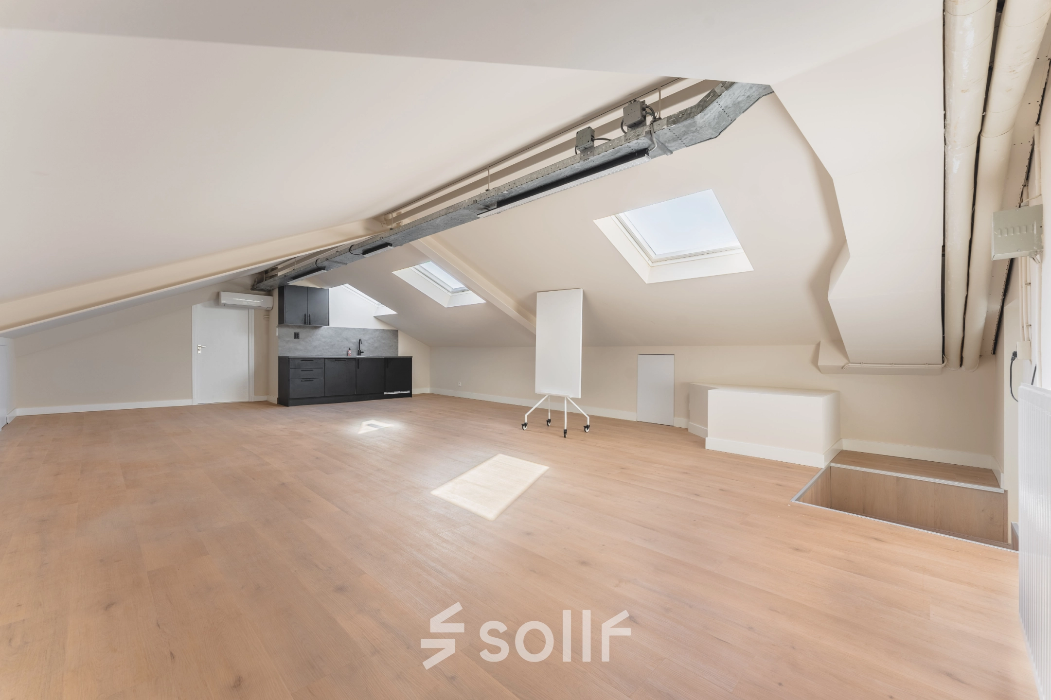 Spacious office space rental at Zeestraat 100, The Hague Center, featuring wooden flooring, skylights, and a kitchenette.