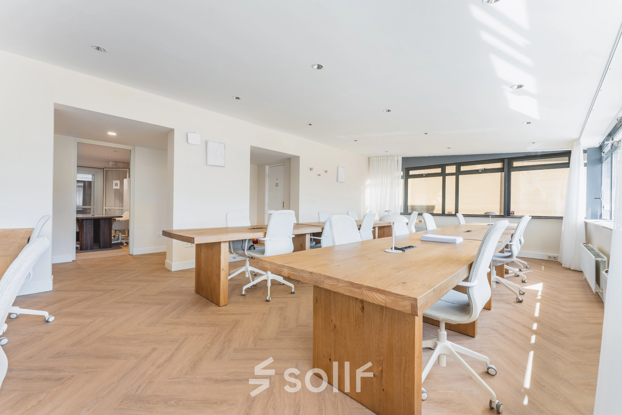 Bright office space to rent at Zeestraat 100, The Hague Center, featuring wooden desks and white chairs in a spacious layout for office space rental.