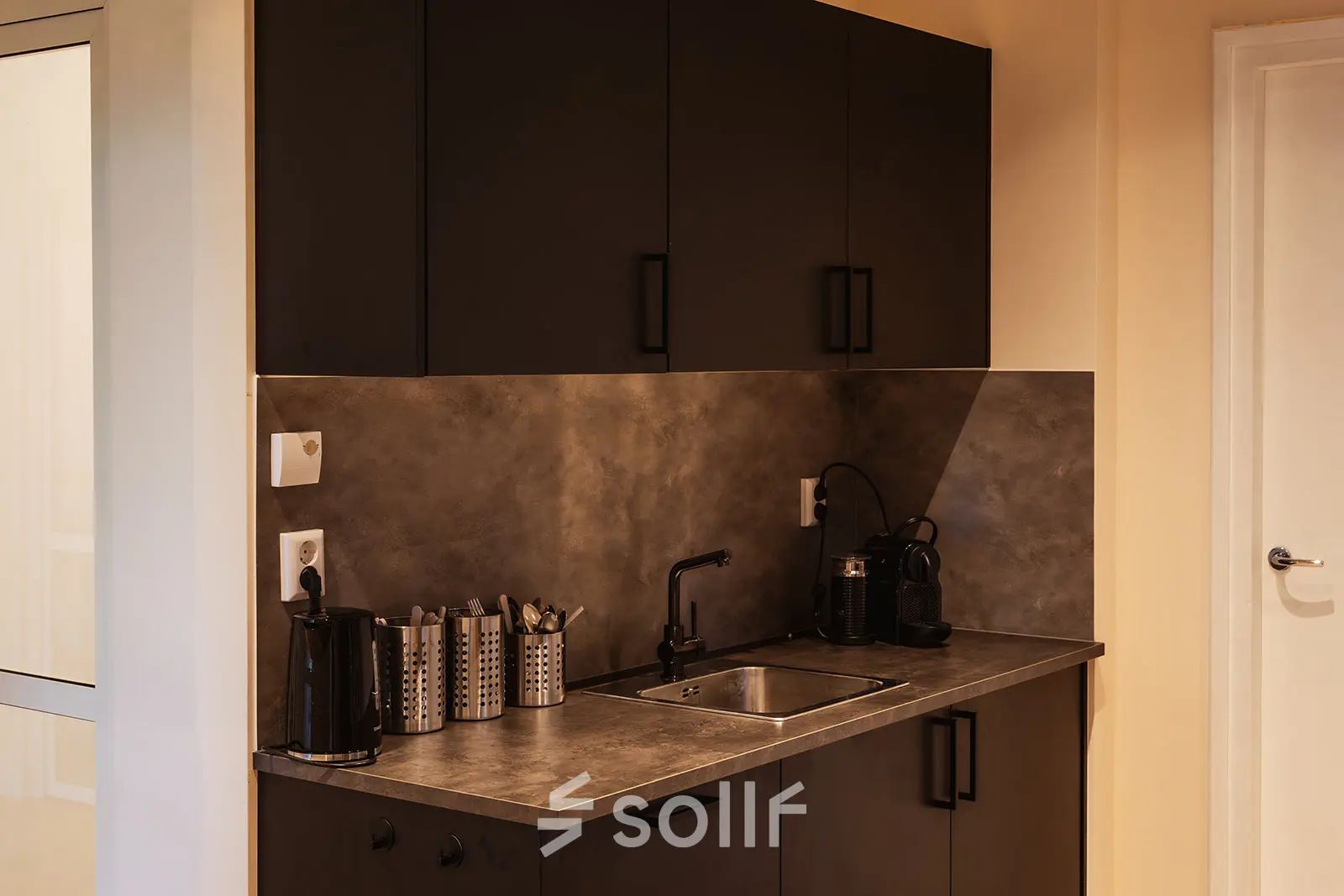 Compact pantry at Zeestraat 100, The Hague Center, ideal for office space rental, featuring a small sink, coffee machine, and storage.