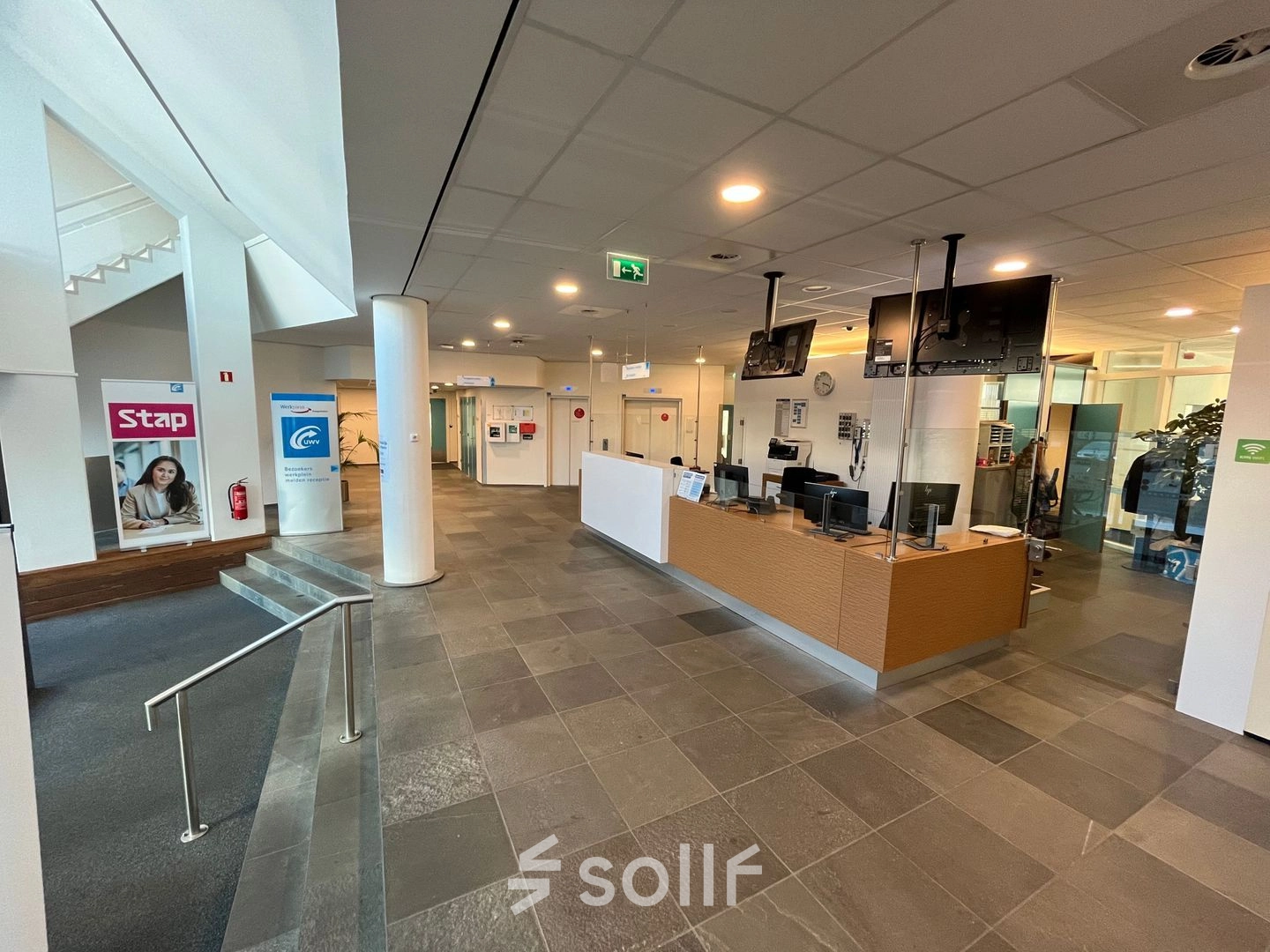 Reception area at Platinaweg 10, The Hague Escamp with a modern desk, banner displays, and accessible walkways. Ideal office space rental with a welcoming environment.