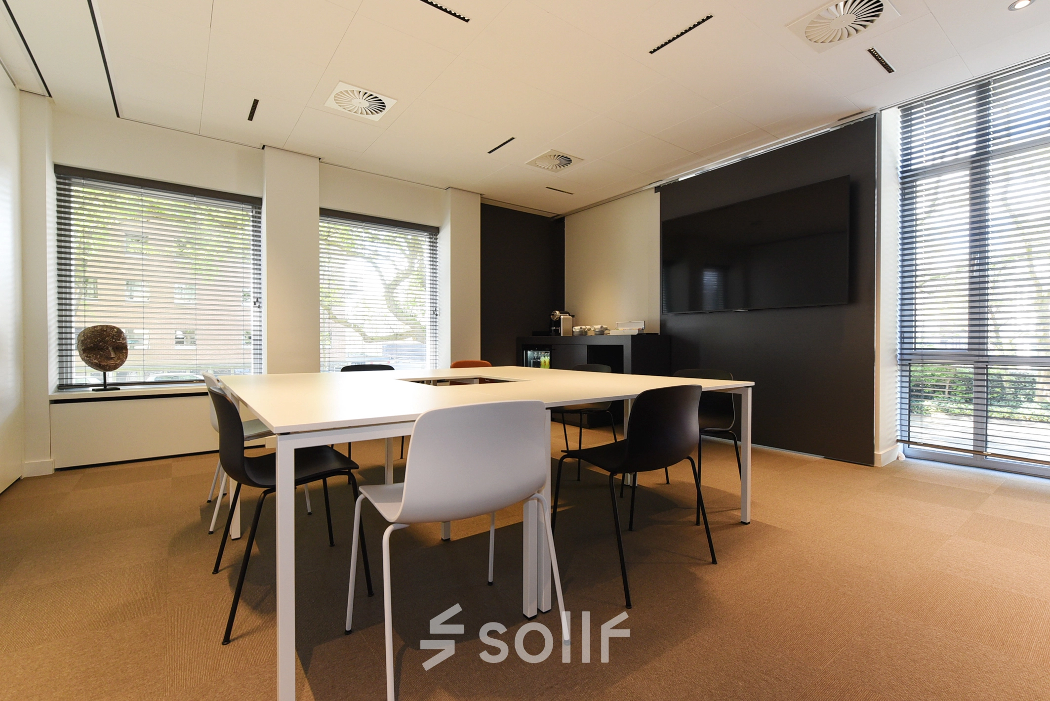 Bright office space for rent in The Hague Statenkwartier featuring a modern conference room with large windows, minimalist tables, and chairs.