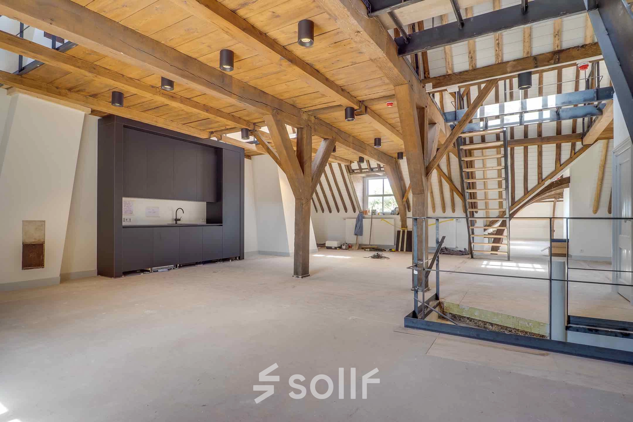 Spacious office interior with wooden beams and a kitchenette, located at Brigittenstraat 22 in Utrecht Center, ideal for office space rental.