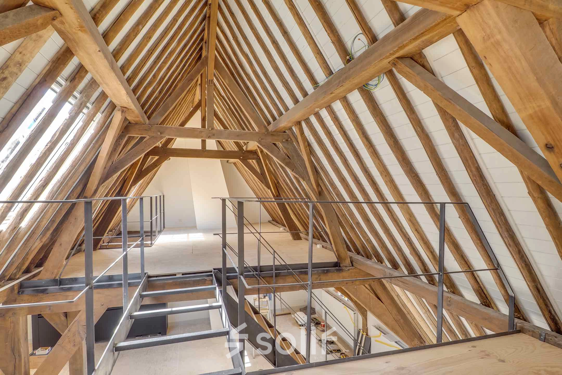 Interior view of an unfurnished attic office space with wooden beams at Brigittenstraat 22 in Utrecht Center. Ideal for office space rental opportunities.
