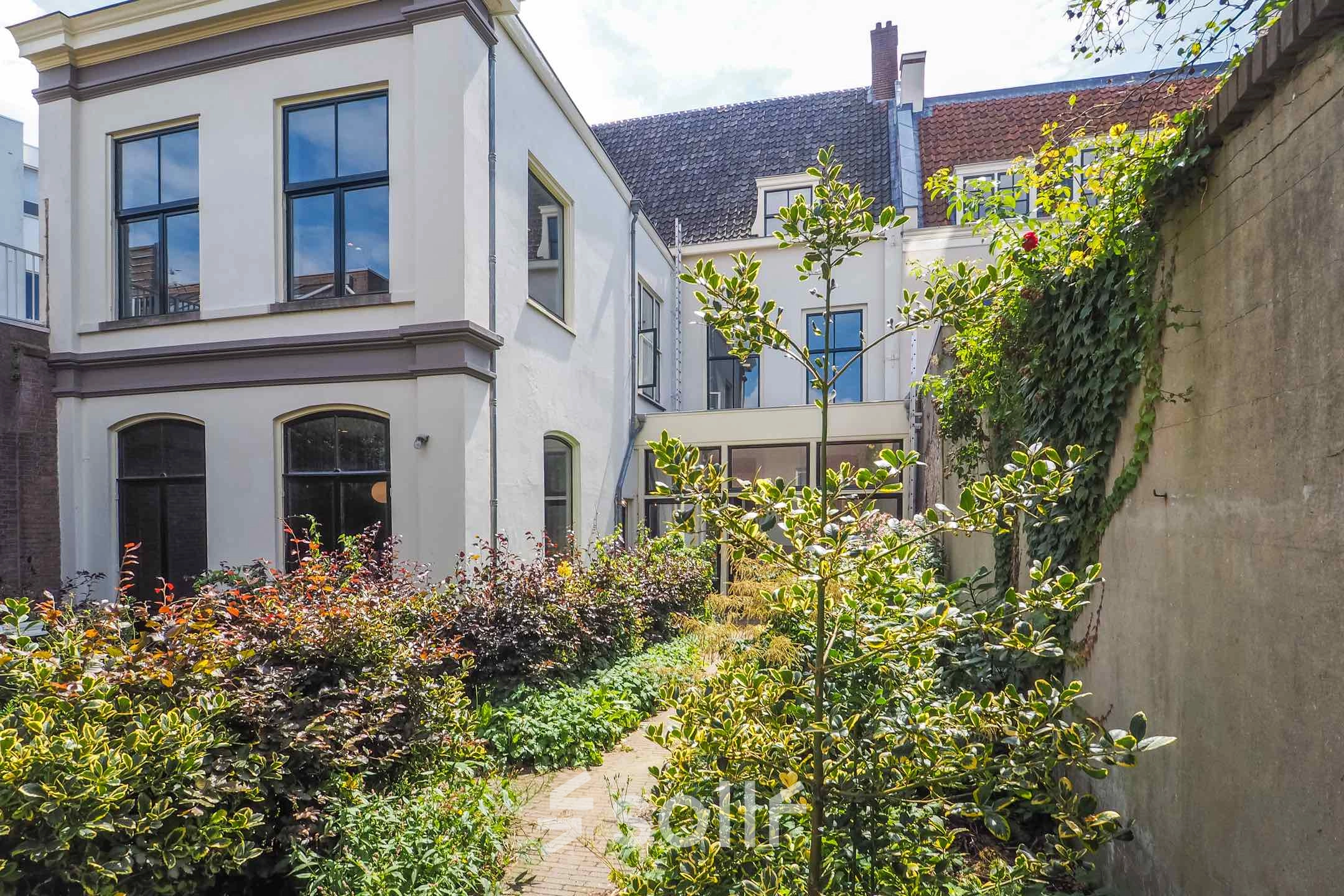 Exterior view of a charming office building at Brigittenstraat 22, Utrecht Center, ideal for office space rental with lush greenery.