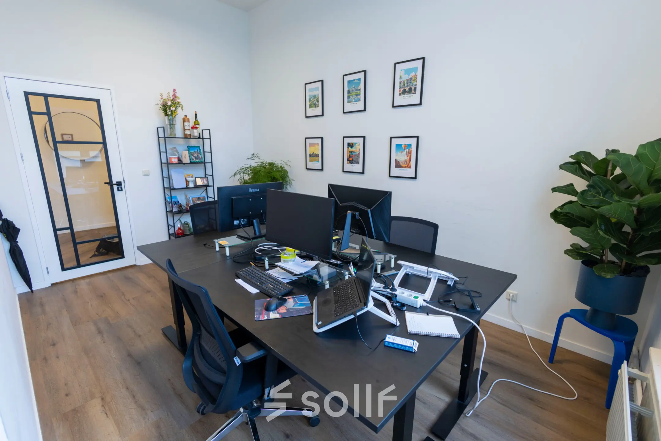 Interior of an office space at Oudegracht 161, Utrecht Center, featuring desks with computers, chairs, and decorative elements on the walls. Ideal for office space rental.