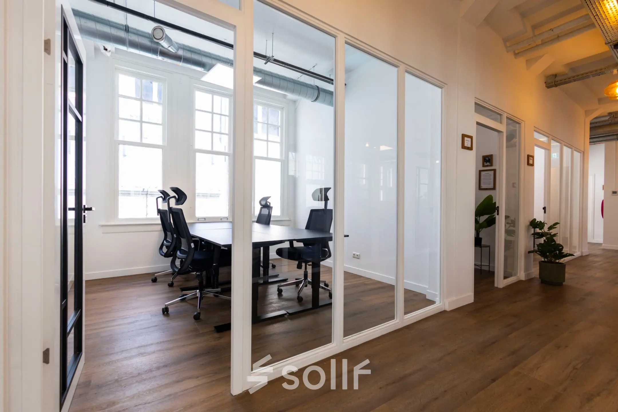 Modern office space at Oudegracht 161, Utrecht Center, featuring glass-walled meeting rooms with ergonomic chairs and wooden flooring, suitable for office space rental.