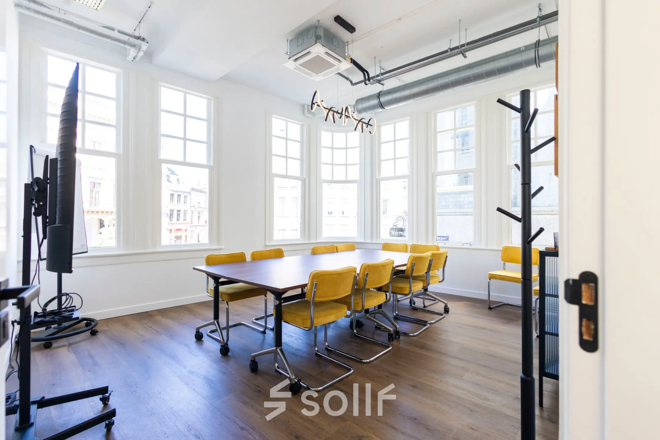 Bright office space for rent at Oudegracht 161, Utrecht Center, featuring a wooden table and yellow chairs, ideal for collaborative meetings.