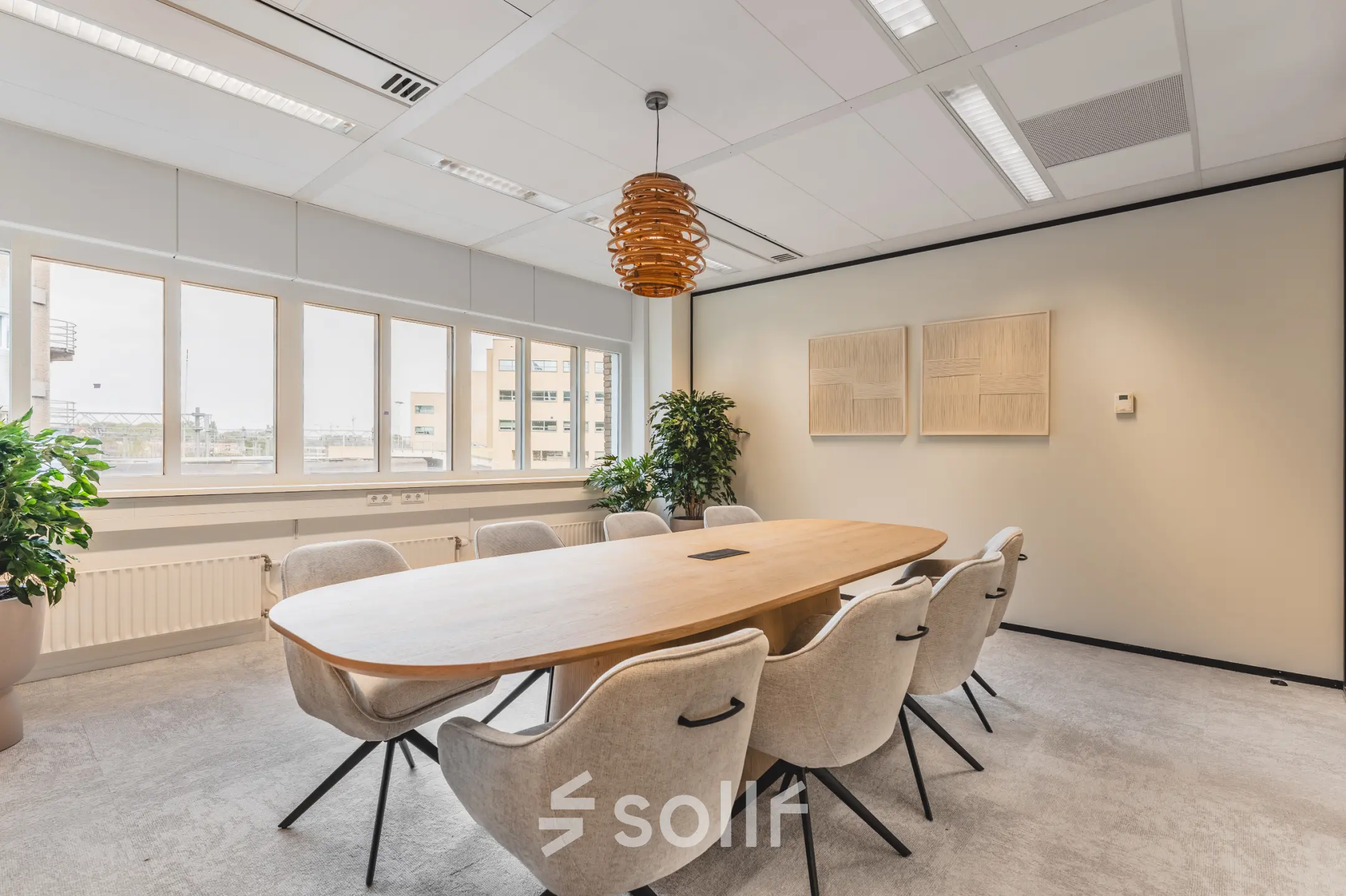 Bright, modern office with large windows and a central meeting table surrounded by chairs, located at Leidseveer 2-10, Utrecht Central Station. Ideal office space rental for productive meetings.