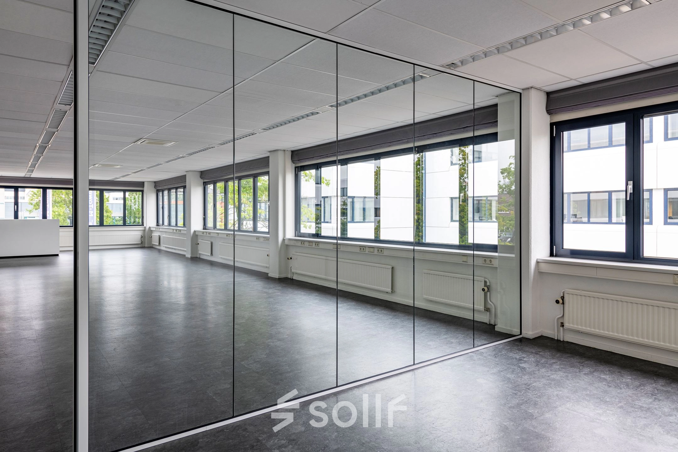 Spacious interior office space with large windows and reflective partitions, offering ample natural light at Atoomweg 350, Utrecht Lage Weide. Ideal for office space rental.