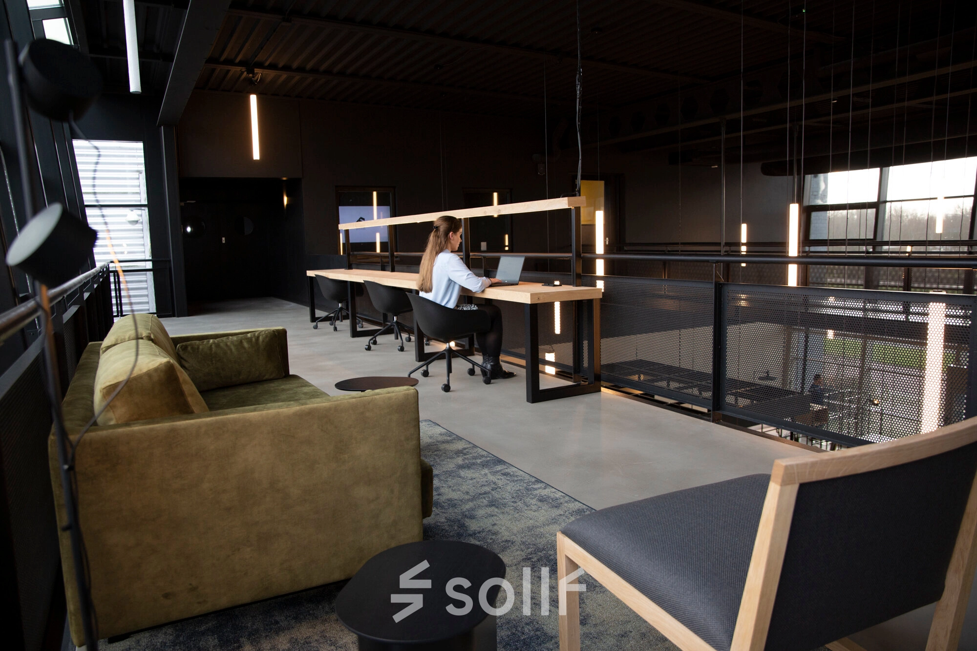 Modern office space rental at Atoomweg 63, Utrecht Lage Weide, featuring a stylish open floorplan with cozy seating and workstations where a person is working on a laptop.