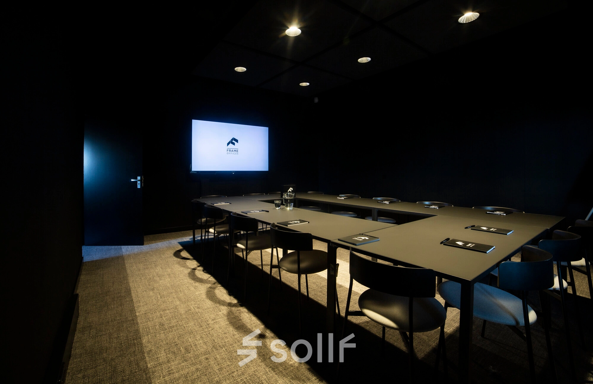 Dark, modern conference room with a large screen and neatly arranged chairs and tables, ideal for office space rental at Atoomweg 63, Utrecht Lage Weide.
