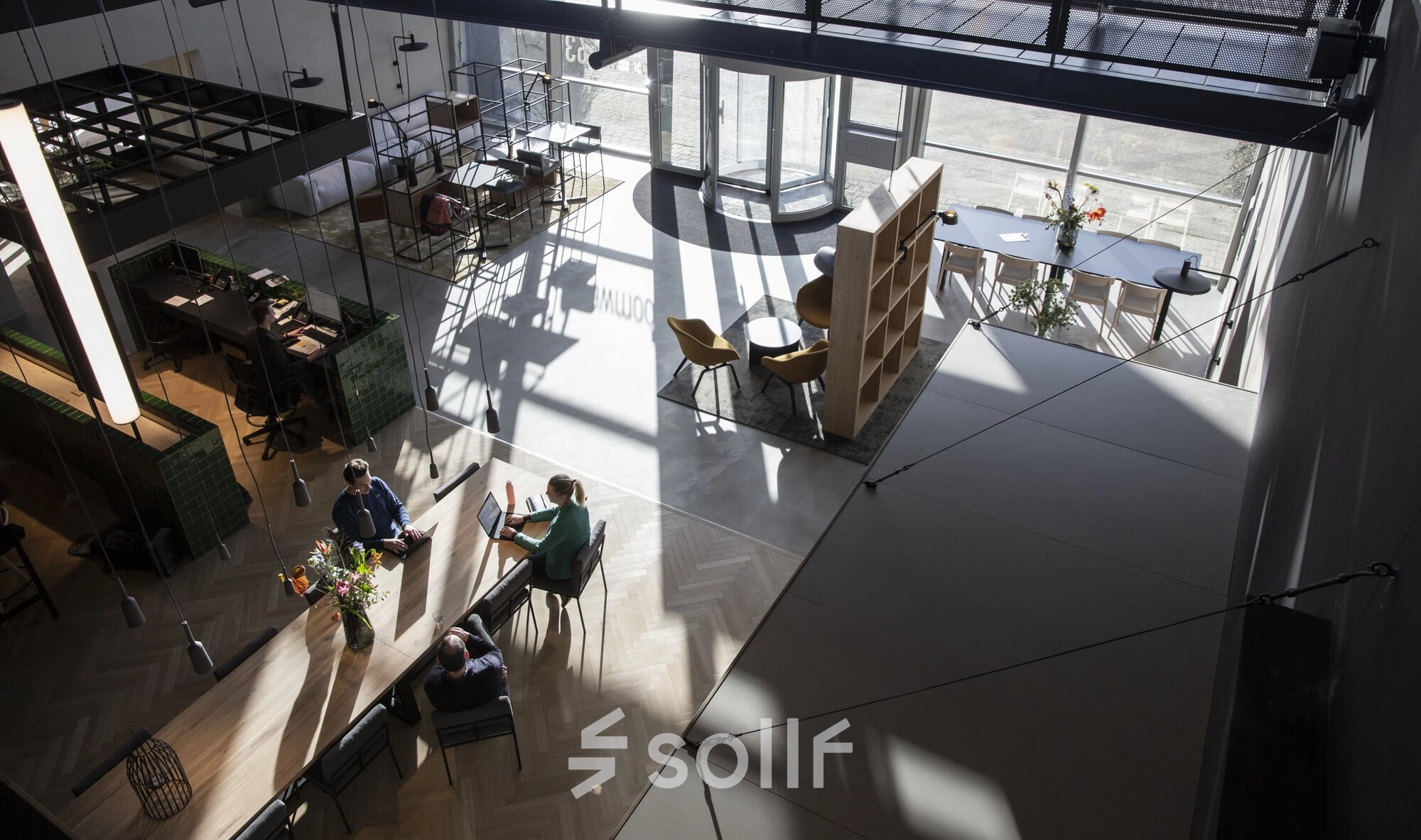 A modern, spacious office to rent at Atoomweg 63, Utrecht Lage Weide, featuring people collaborating at a large table in a naturally lit open floorplan.