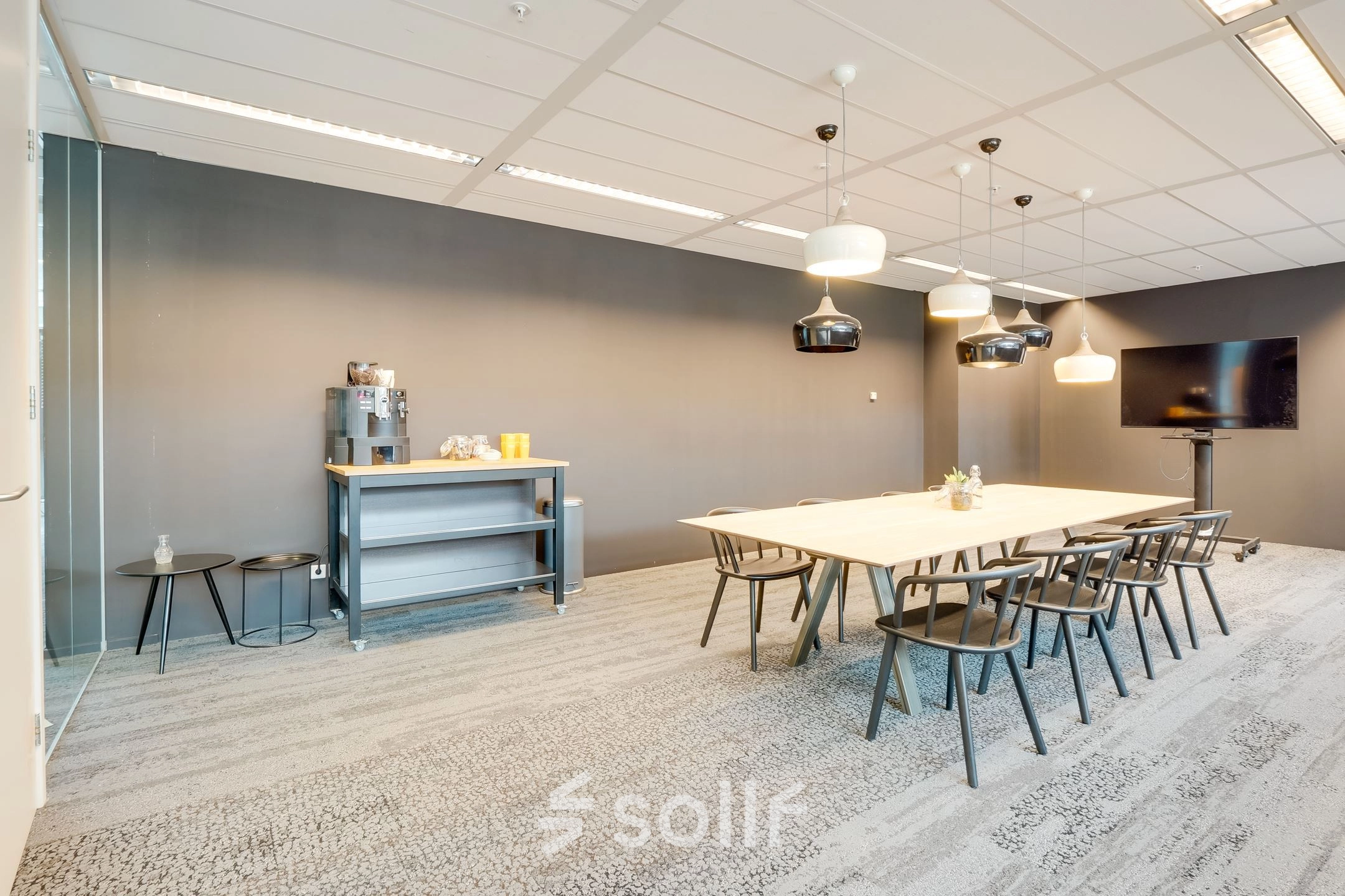 Modern office space rental at Computerweg 22, Utrecht Lage Weide, featuring a large meeting table and chairs, a beverage station, and a wall-mounted screen.