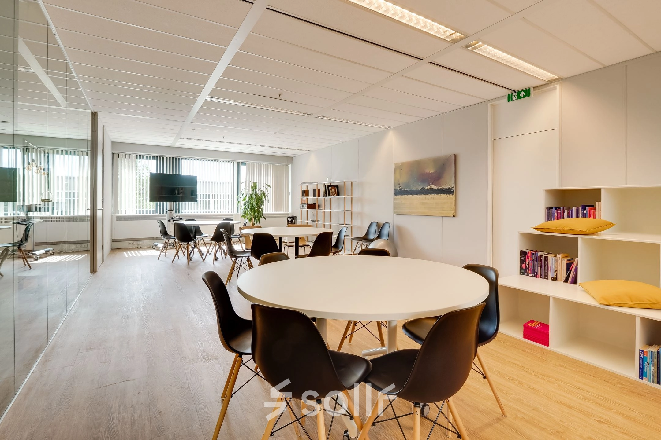 Modern office space for rent in Utrecht Lage Weide at Computerweg 22, featuring round tables, black chairs, and a wall-mounted TV, ideal for collaborative work.