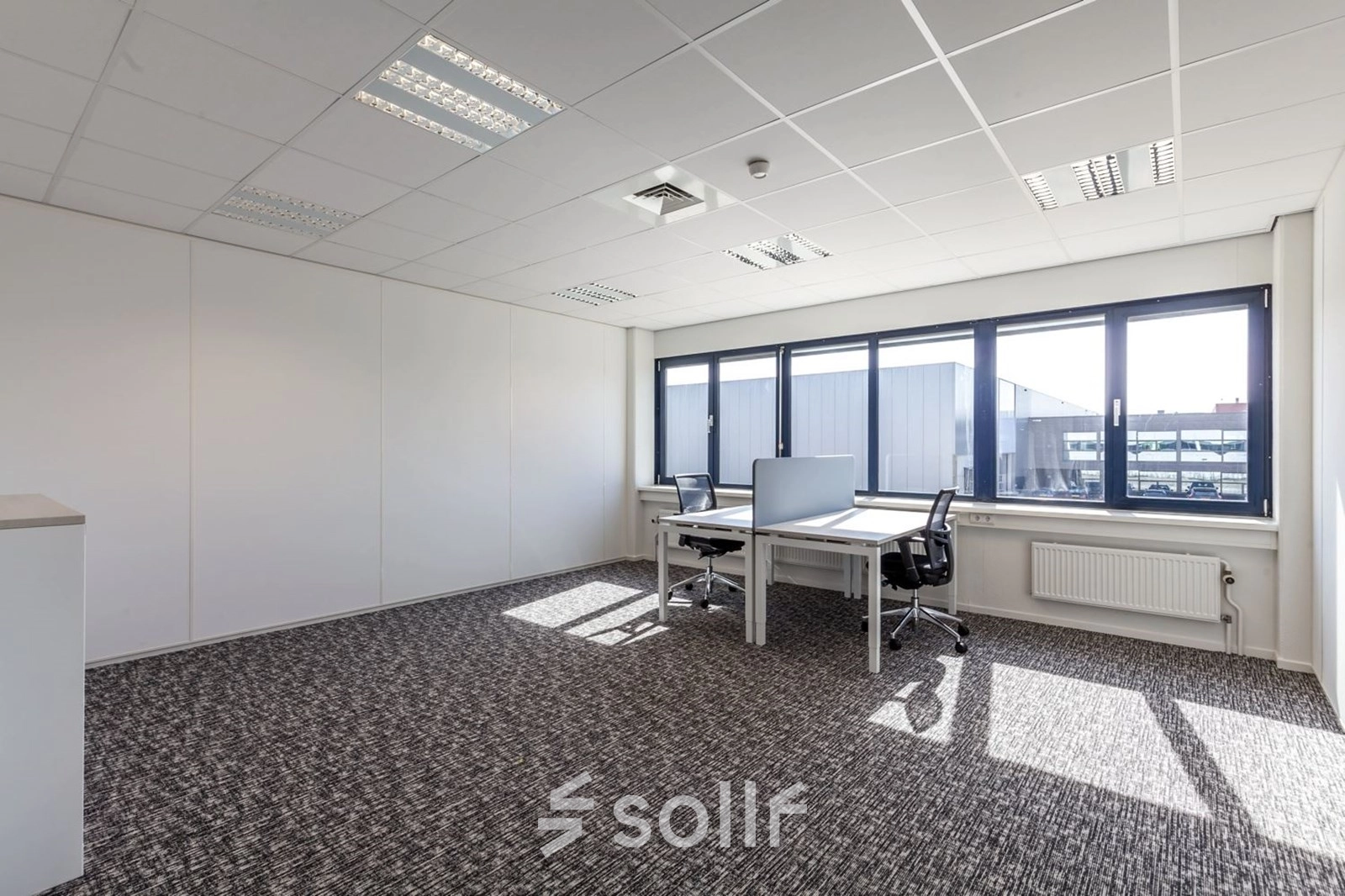 Bright office space with carpeted flooring and two desks, ideal for office space rental at Reactorweg 301, Utrecht Lage Weide.
